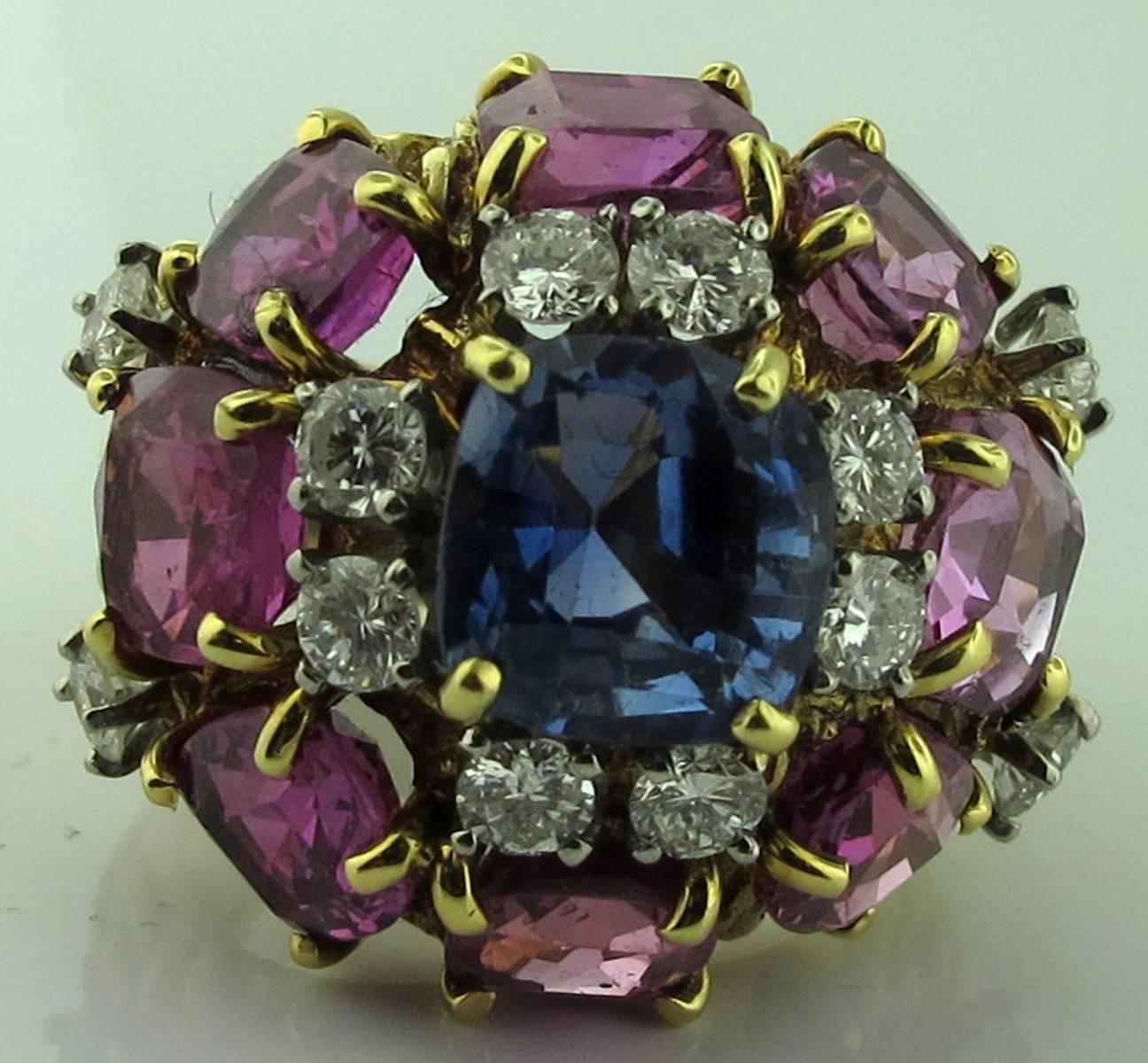 Multi-colored Sapphire Ring with diamonds.  Set in 18 karat yellow gold.  Center Cushion Cut Blue Sapphire is 3.00 carats.  There are 8 Pink Sapphires that weigh 10.00 carats in total.  There are 12 Round Brilliant diamonds weighing 2.00 carats. 