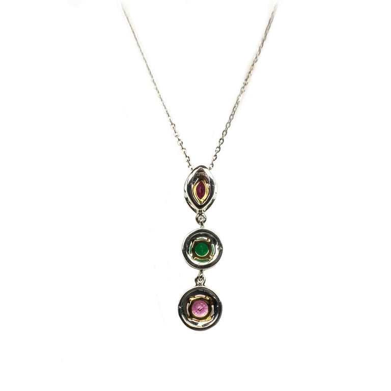 Elegant three drop links pendant. Ruby, Emerald, Pink sapphire mounted in open basket with prongs, accented with halo design in round brilliant cut diamonds, set in 18 karat white gold. Pendant chain is 18 karat white gold, 16