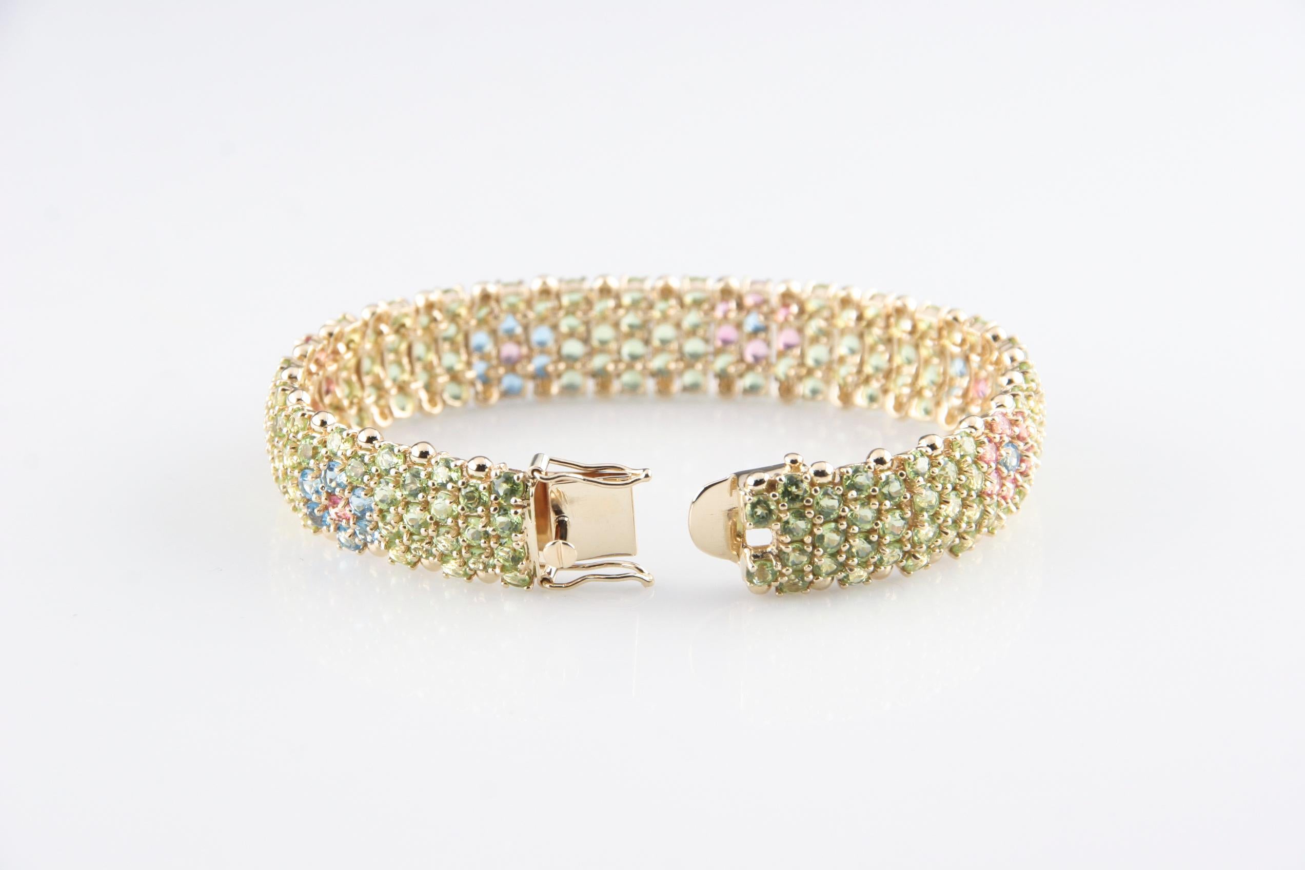 Gorgeous 14k Yellow Gold Gemstone Bracelet
Features Rows of Three or Four Round Brilliant Gemstones that Create a Unique Floral Design
Features Greenish Yellow Quartzes, Pink Tourmaline, and Blue Topaz
Total Length = 7