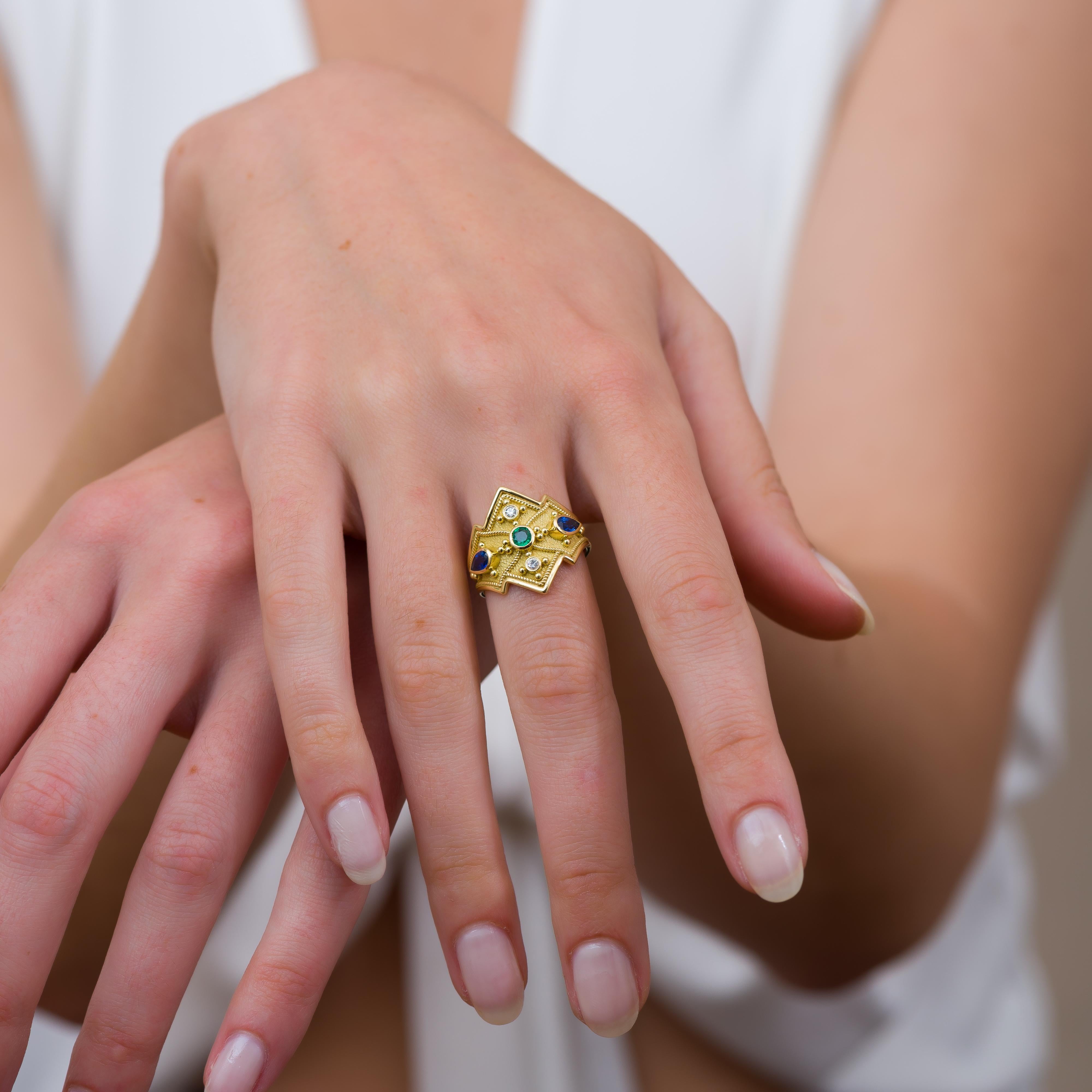 Behold the regal charm of our gold ring, featuring a crown design adorned with two pear sapphires, a round emerald, sparkling brilliance, and intricate golden details—a masterpiece that crowns your hand with timeless sophistication and