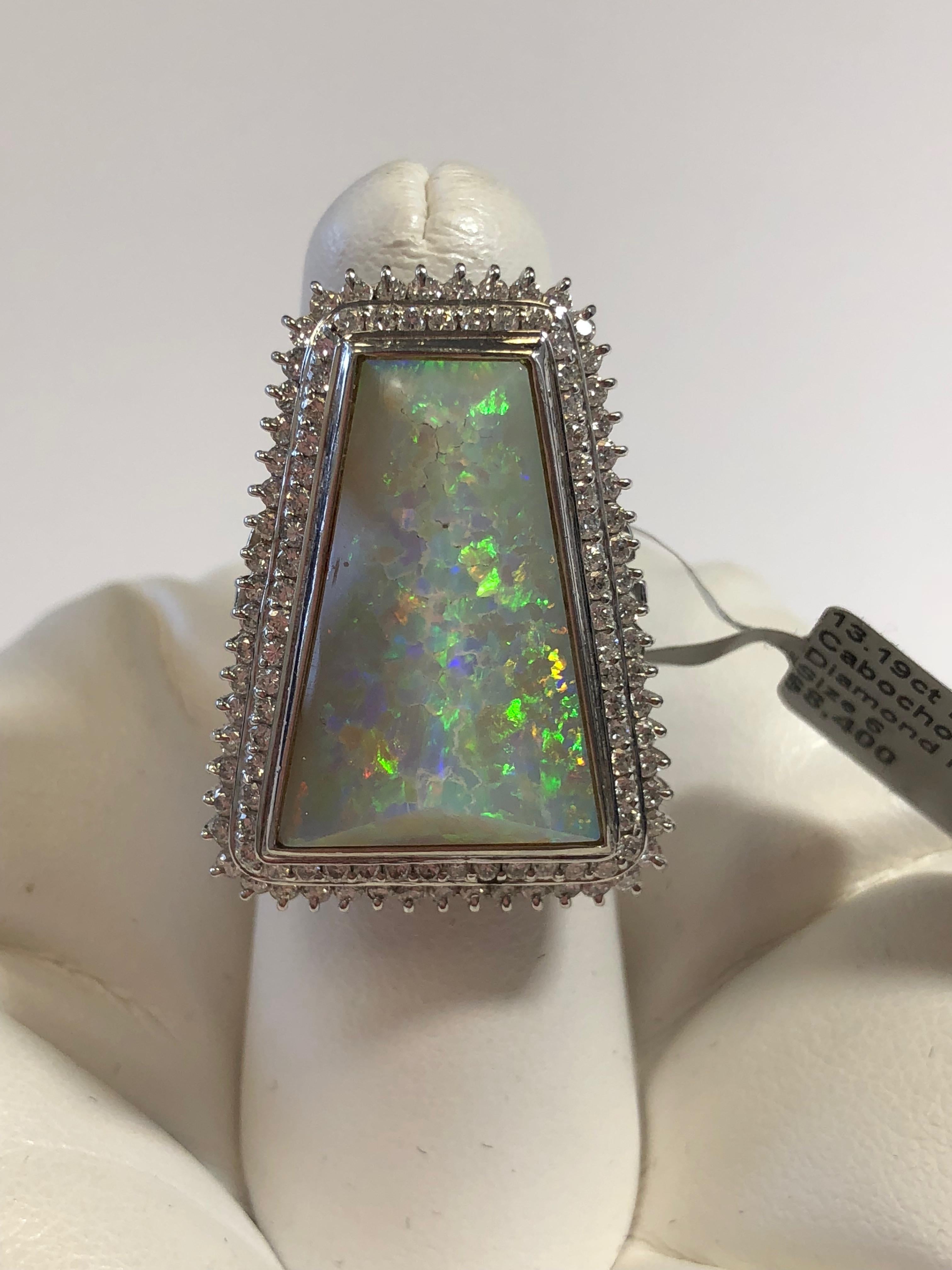 Stunning 13.19 carat multicolor opal cabochon in a very unique cut.  It has a  white background with sparks of green, orange, purple and yellow.  Surrounded by 1.30 carats of white diamonds in a beautiful size 6 platinum mounting.  A great cocktail
