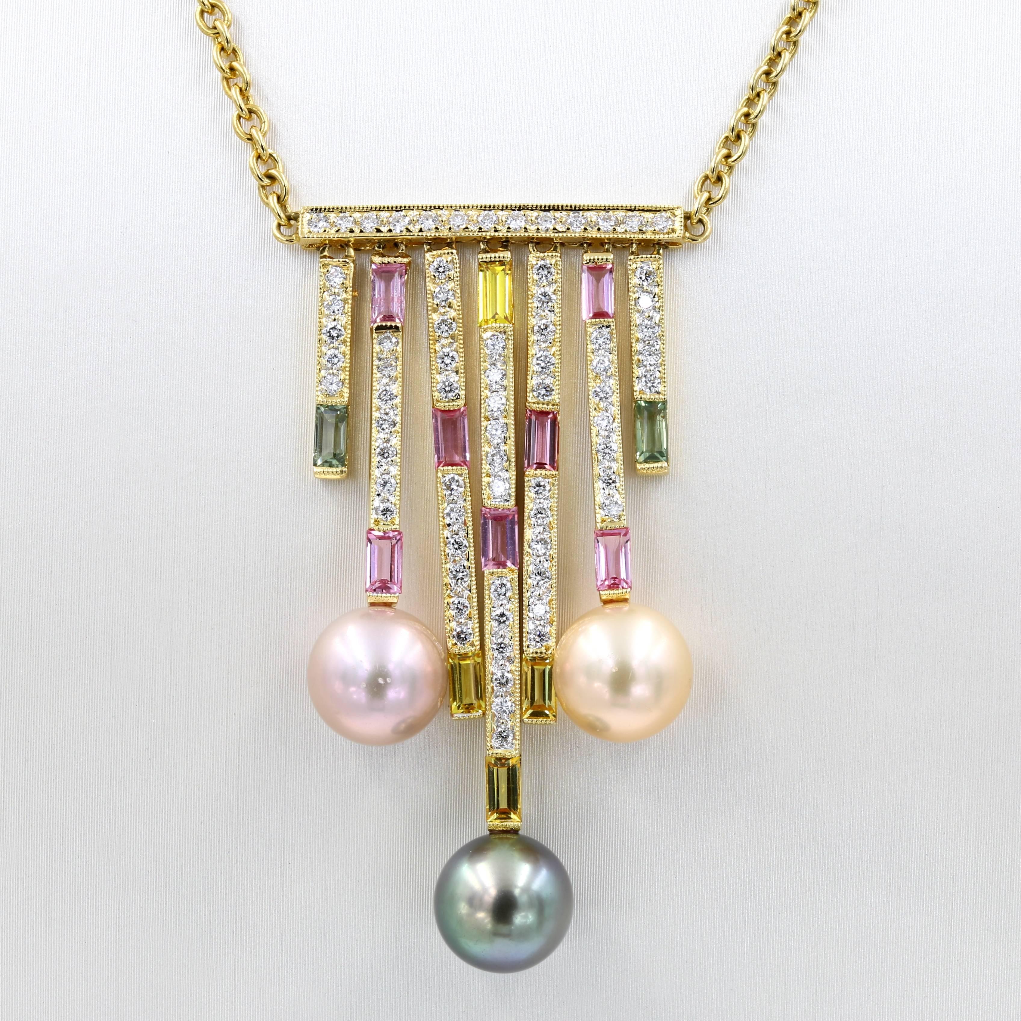 This unique necklace in 18kt. yellow gold has three 9mm freshwater pearls (1 tan, 1 cream, and 1 pink) which dangle from white diamond and multicolored sapphire sections. The pieces contains 71 rounds diamonds=.72ct. t.w. There are 21 natural