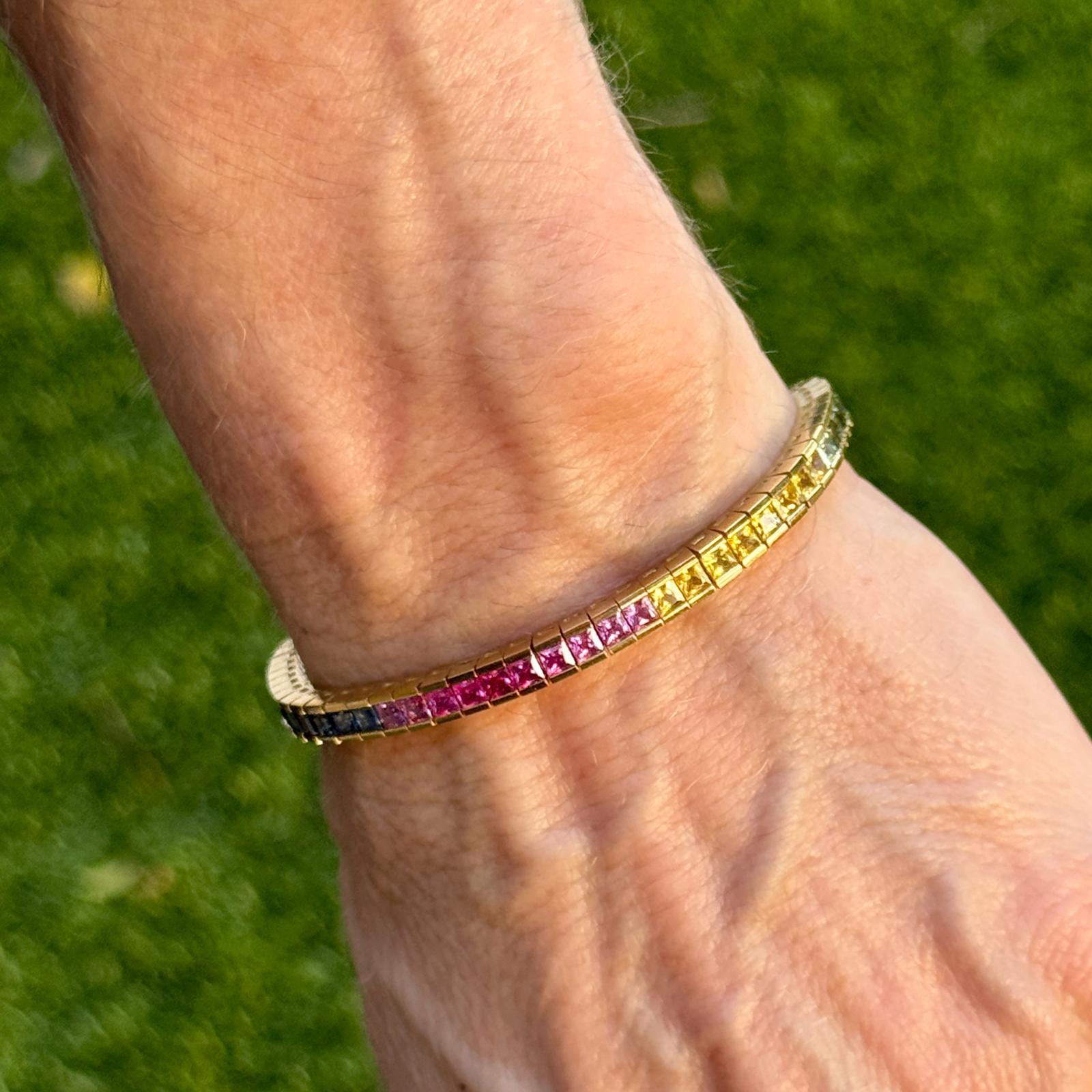 Dieses exquisite, mehrfarbige Saphir-Tennisarmband ist aus 18 Karat Gelbgold gefertigt und präsentiert eine Vielzahl von Saphiren in einem nahtlosen Design. Die sorgfältig gefassten Edelsteine durchlaufen ein komplettes Farbspektrum und sorgen für