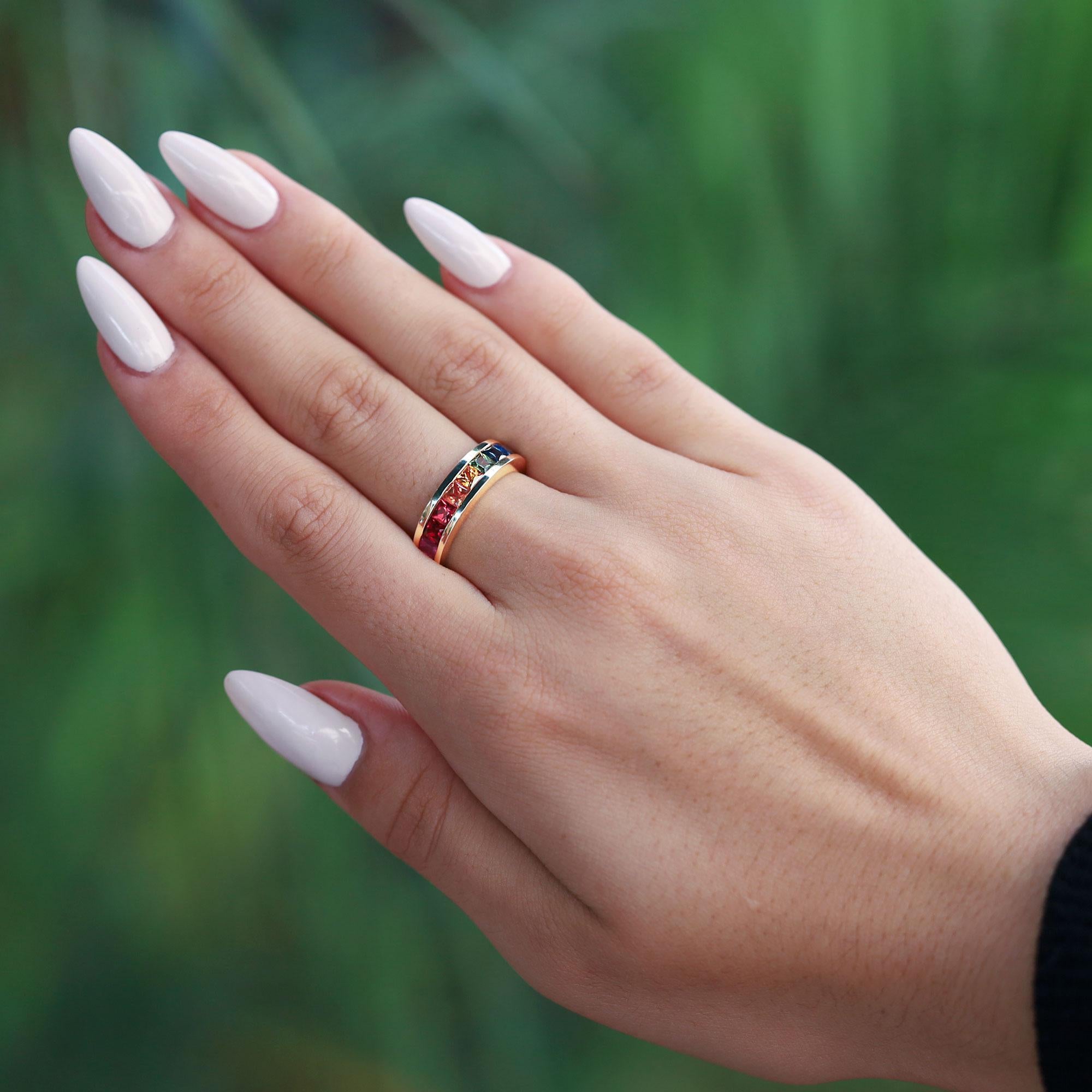 A stunning anniversary - wedding band, or right hand stacking statement ring, showcasing a rainbow of 9 vivid, multi color sapphires, meticulously matched and faceted for maximum vibrance and color dispersion. The channel setting sits low on your