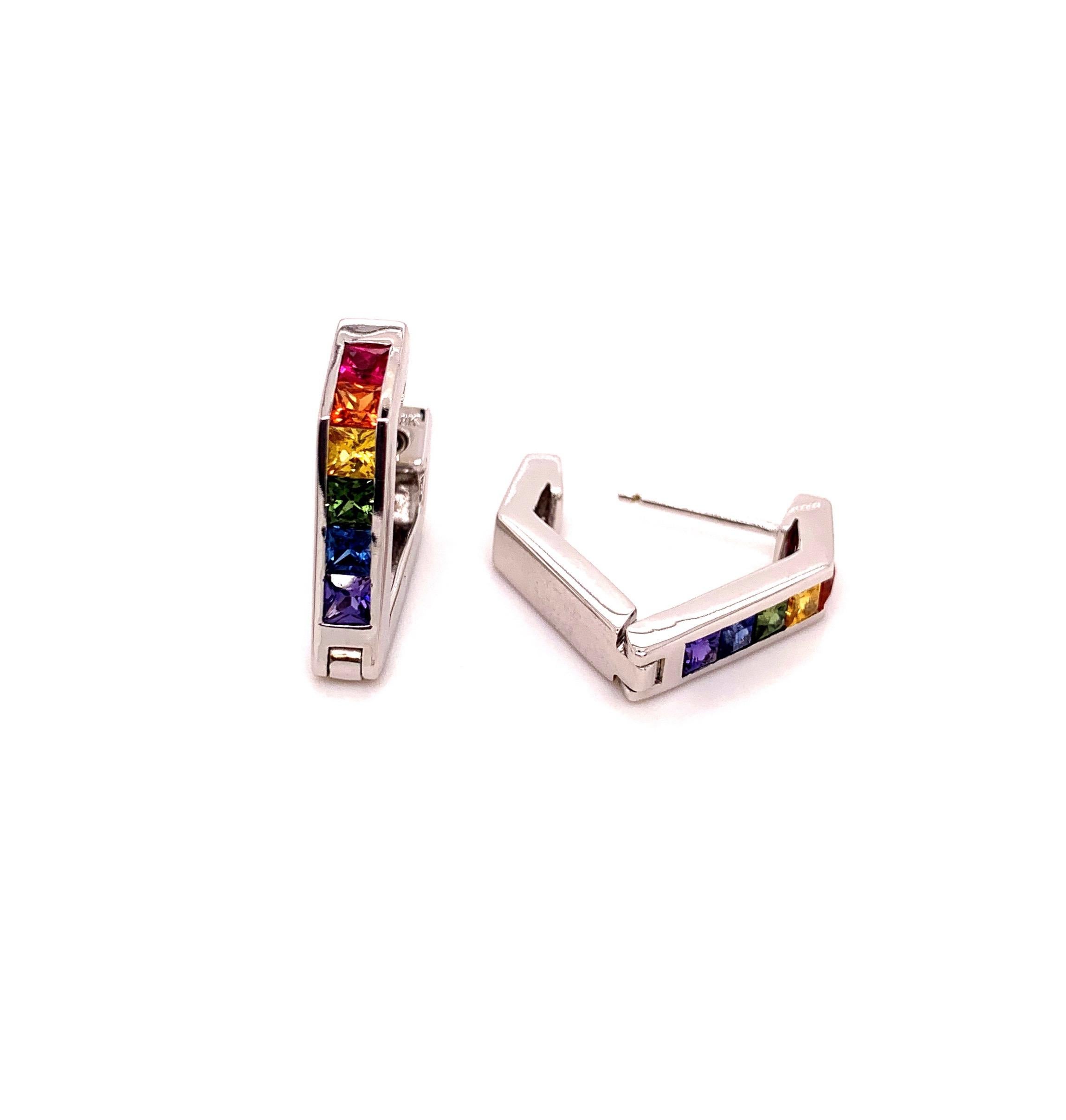 These multi color Hoop - Earrings have a contemporary shape and they are not the traditional round huggies. Done in 18-karat white gold this pair has a total of 1.63 carats of 12 princess cut 2.6 mm multi colored Sapphire, point to point 17 mm long.