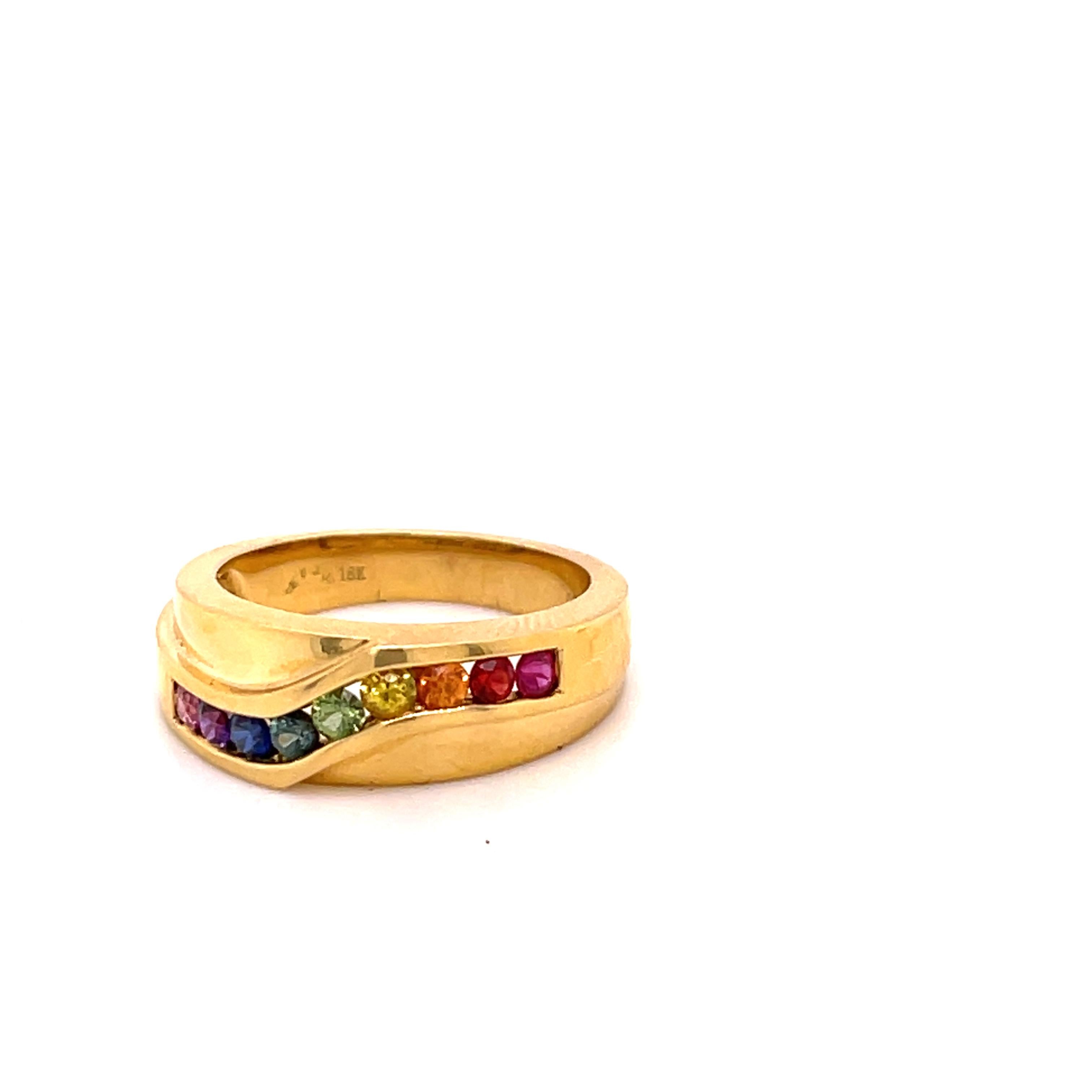 This multi-color Sapphire Ring has a contemporary shape. Done in 18-karat yellow gold this ring has a total of 0.59 carats of 9 round cut 2.3mm multi-colored Sapphires. The ring has a width of 6.8 mm and tapers down to 4.1 mm. 
The ring is a size 6