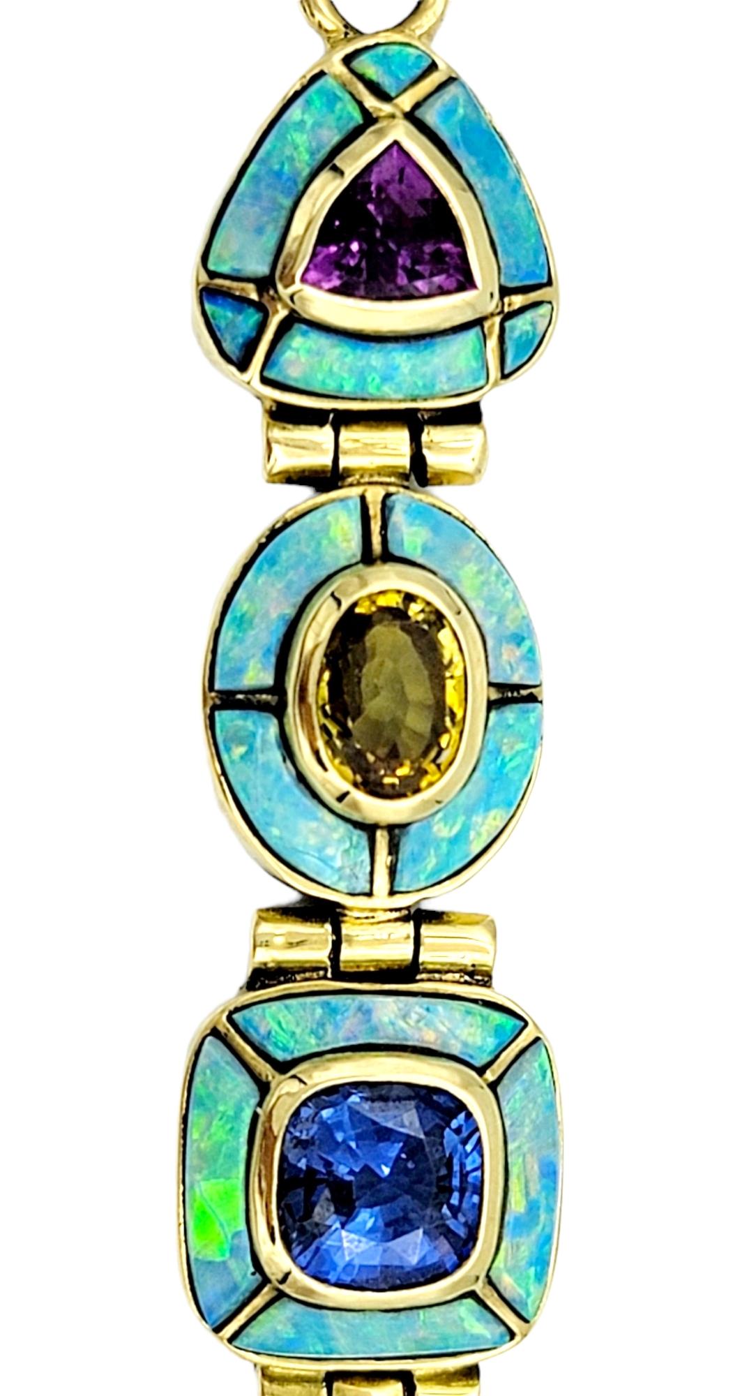 This 18 karat yellow gold pendant is a true work of art. Adorned with an exquisite array of sapphire gemstones, a captivating tourmaline, and encircled by a delicate inlay of blue opal, this piece would make an excellent addition to your fine