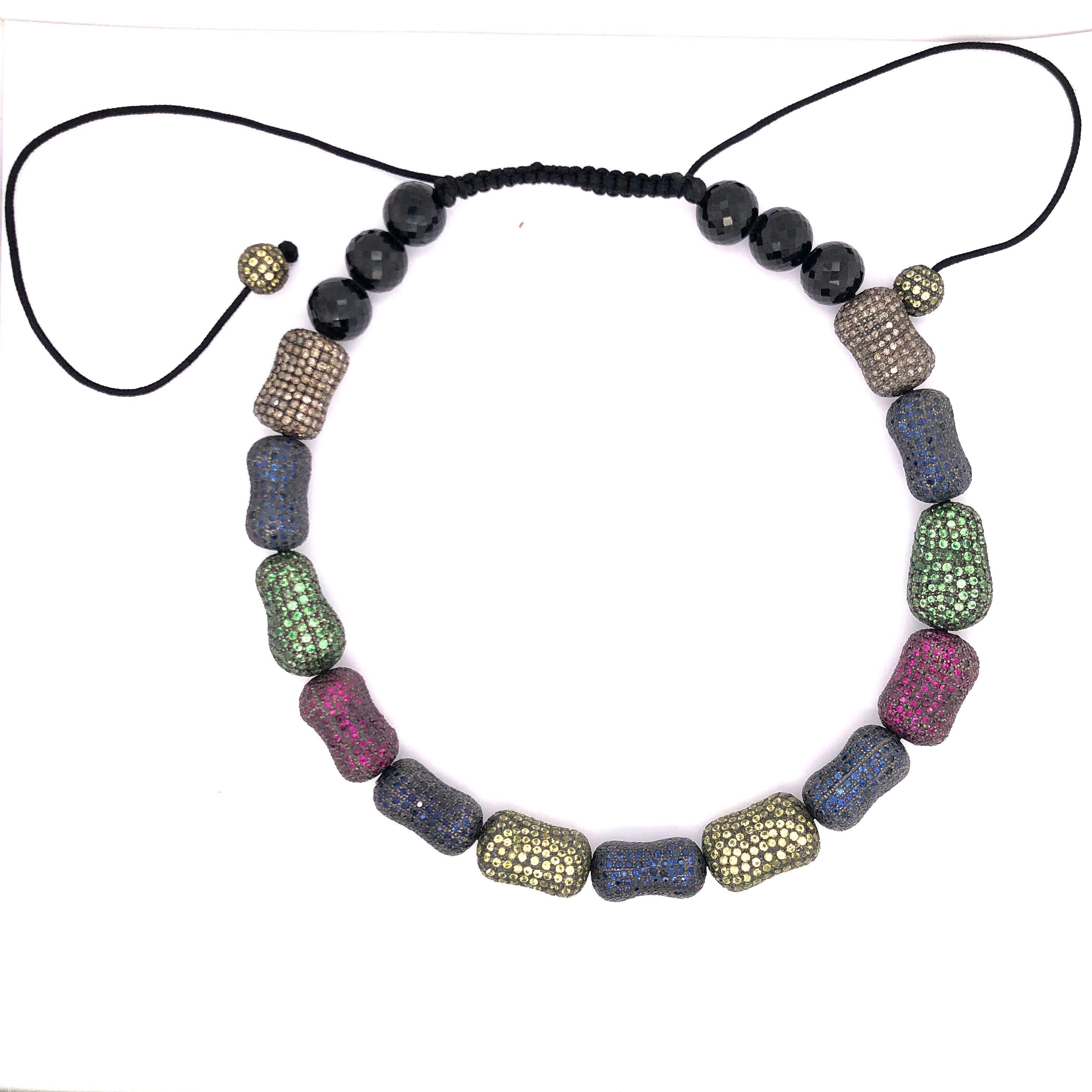 Very Stylish this Multi Color Stones like Sapphire, Tsavorite, Ruby  Macrame Choker is fun and very trendy. This Choker has multi sapphire pave beads with onyx stones at back and 2 round beads hanging. This choker is beaded via black cotton cord and