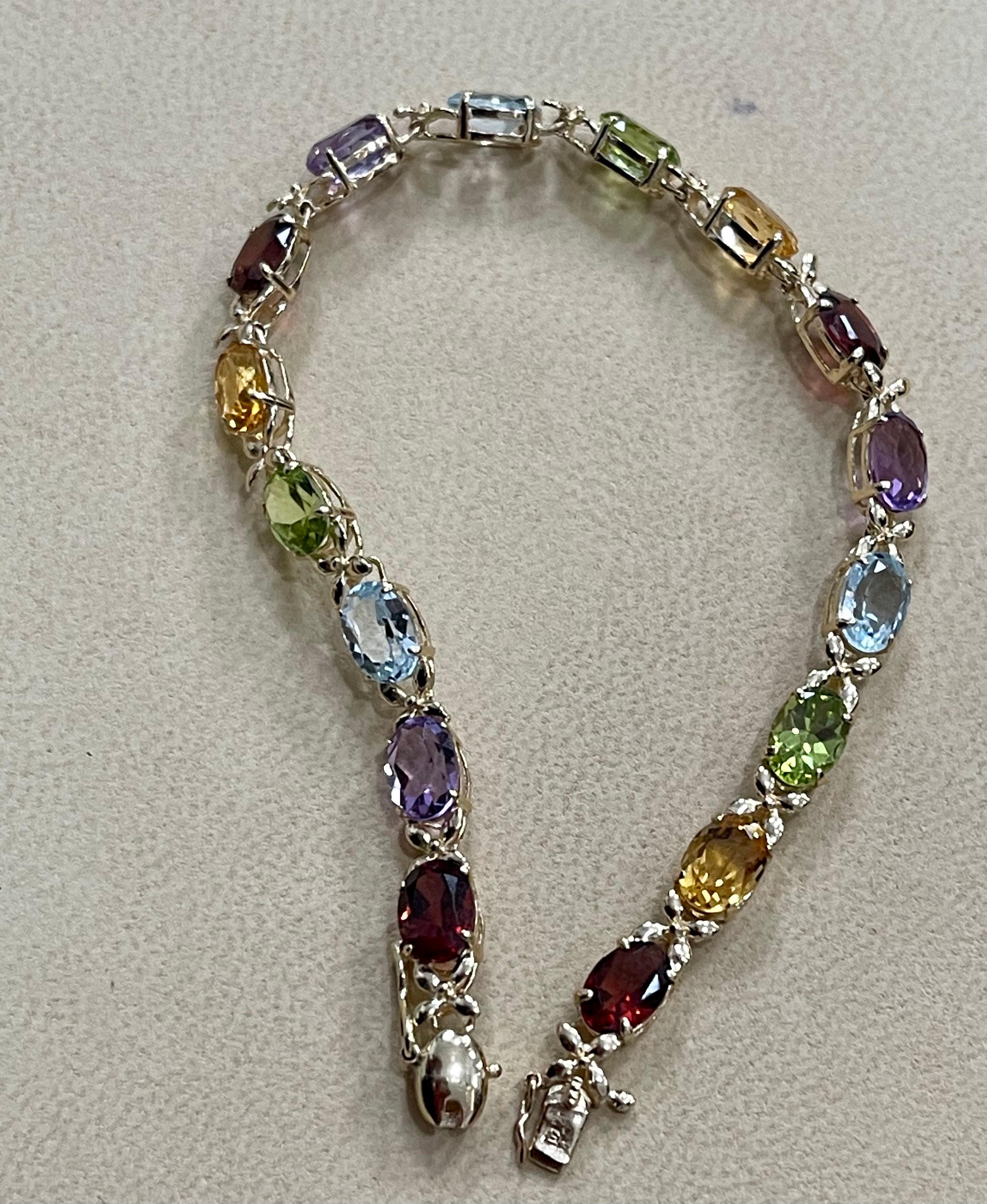  This exceptionally affordable Tennis  bracelet has  16 stones of oval  Blue Topaz ,Peridot, Garnet, Citrine, and Amethyst  . Each stone is spaced by a X shape structure made by Gold. The weight of the multi semi precious  is approximately  9 Carat