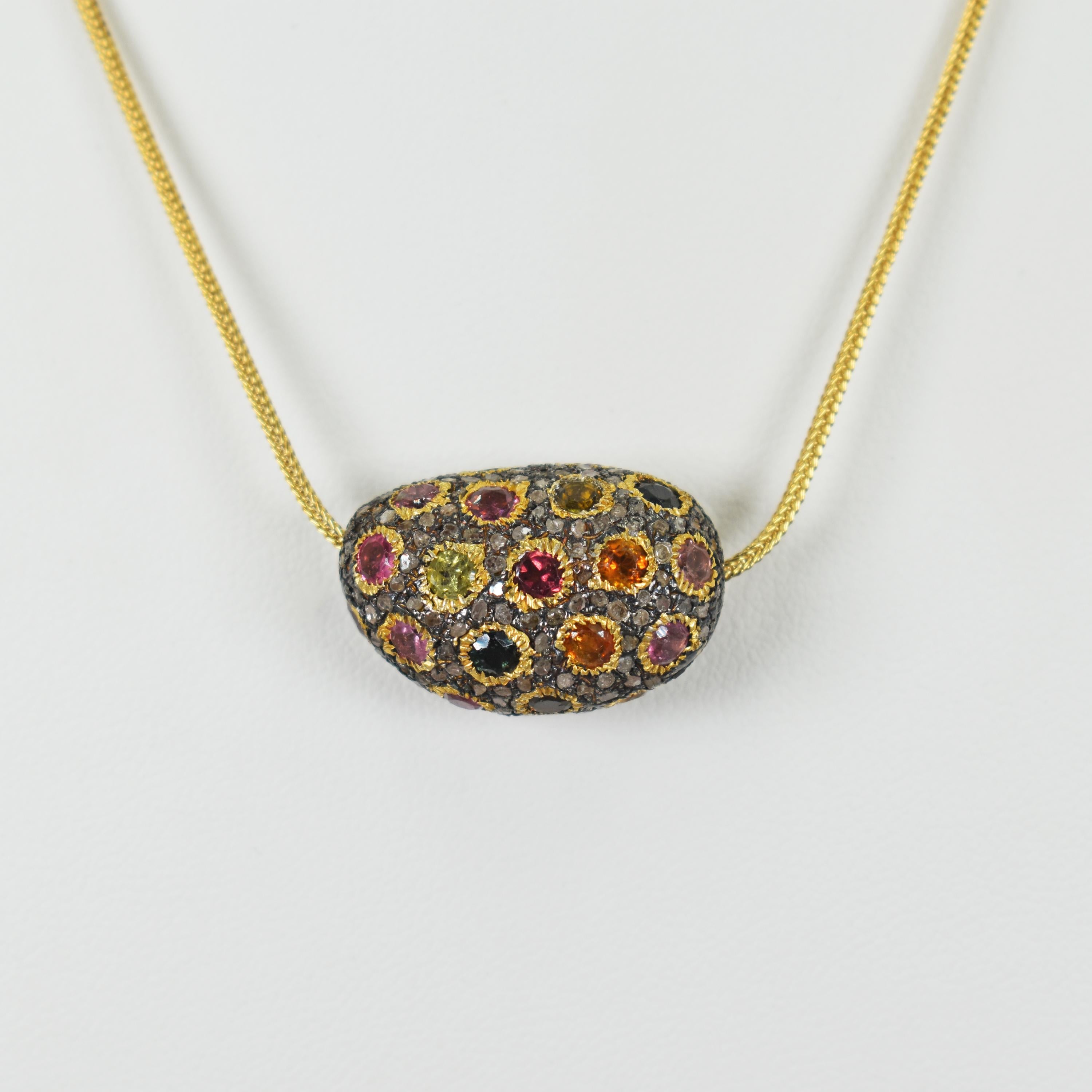 A rainbow spectrum of round faceted Green, Orange, Pink, Indicolite Blue, Yellow and Rubellite Tourmaline with accent grey pavè Diamonds set in an oxidized sterling silver and 18k yellow gold pebble shaped bead pendant necklace. There are