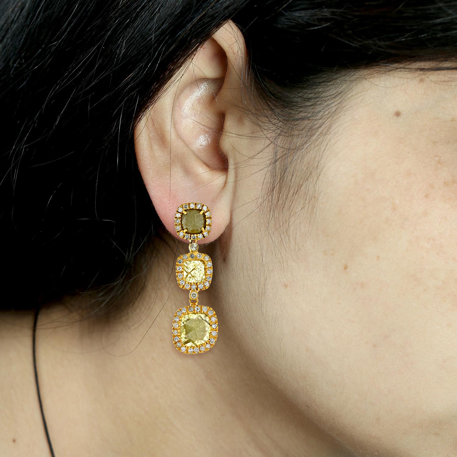 Ces boucles d'oreilles présentent des diamants de glace en forme de coussin, sertis dans de l'or jaune 18k. Les diamants ont un aspect multicolore, probablement dû à l'utilisation de traitements rehaussant la couleur tels que l'irradiation et le