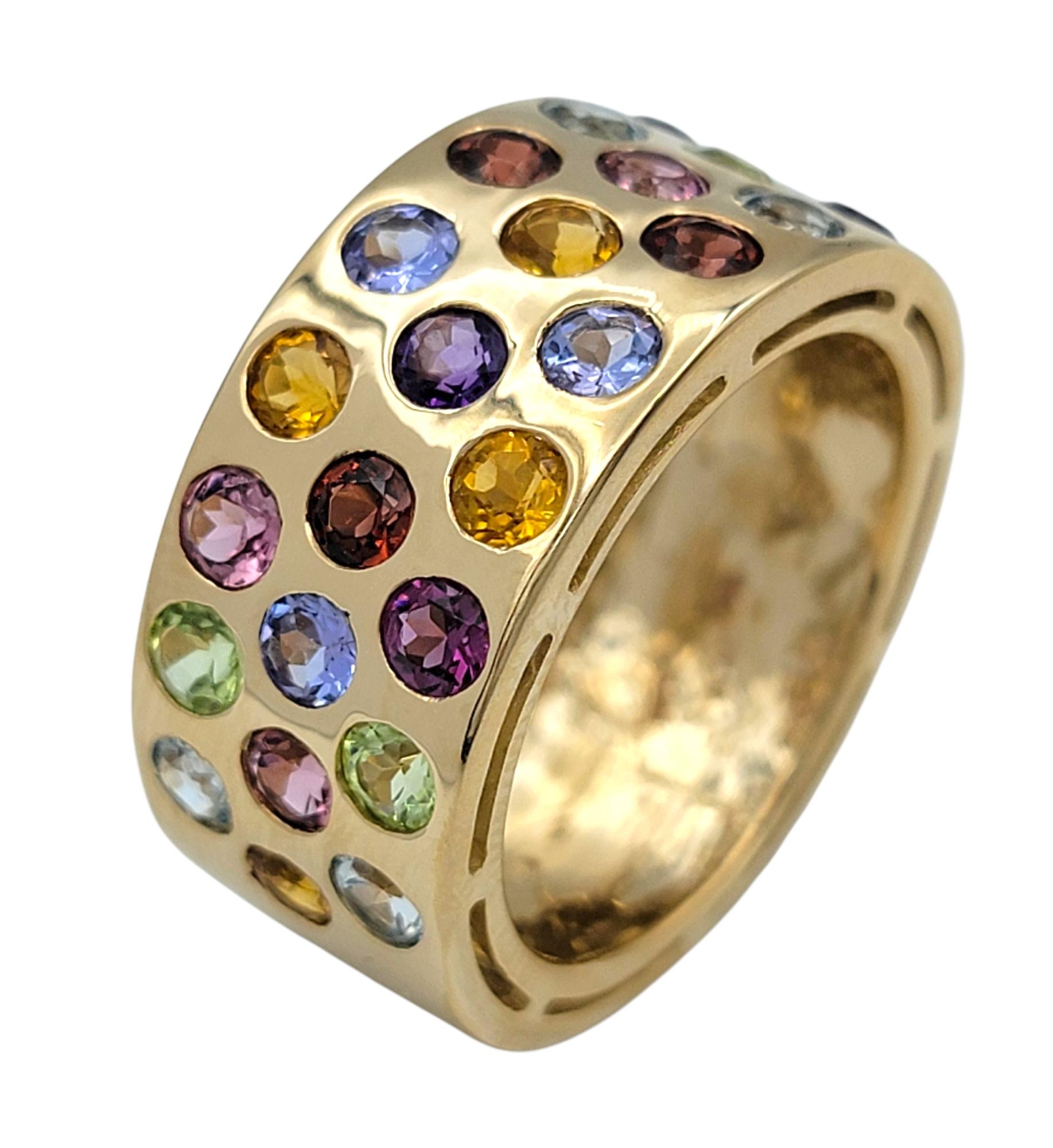 Misura dell'anello: 8

Questo anello a fascia larga, dal design giocoso e vivace, mette in mostra un vivace mosaico di gemme a taglio rotondo in un arcobaleno di colori. Incastonate in oro giallo da 14 carati, le pietre sono incastonate a filo in un
