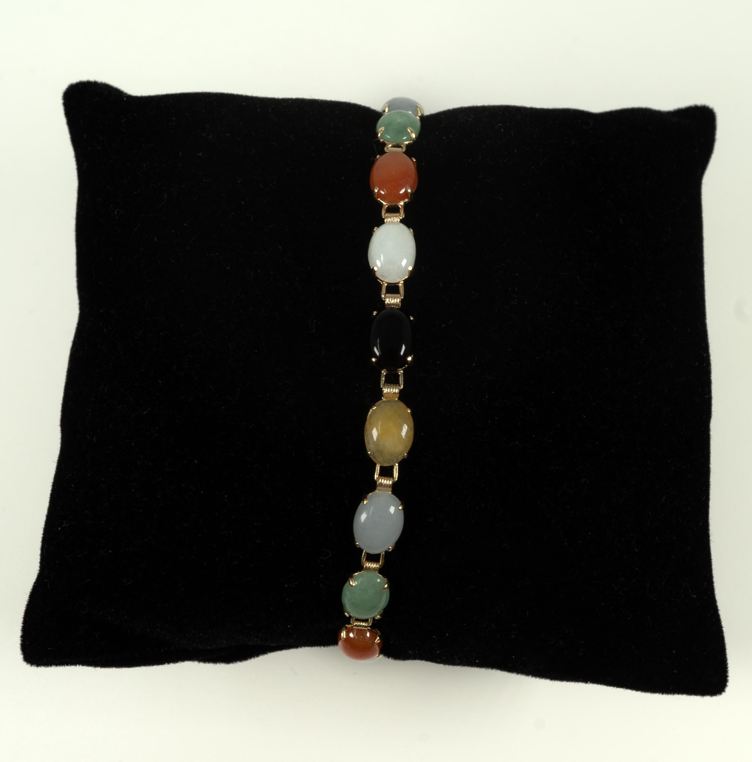Composed of 14 karat yellow gold, this beautiful bracelet features prong-set, oval-shaped, cabochon-cut, multi-color jade stones. 