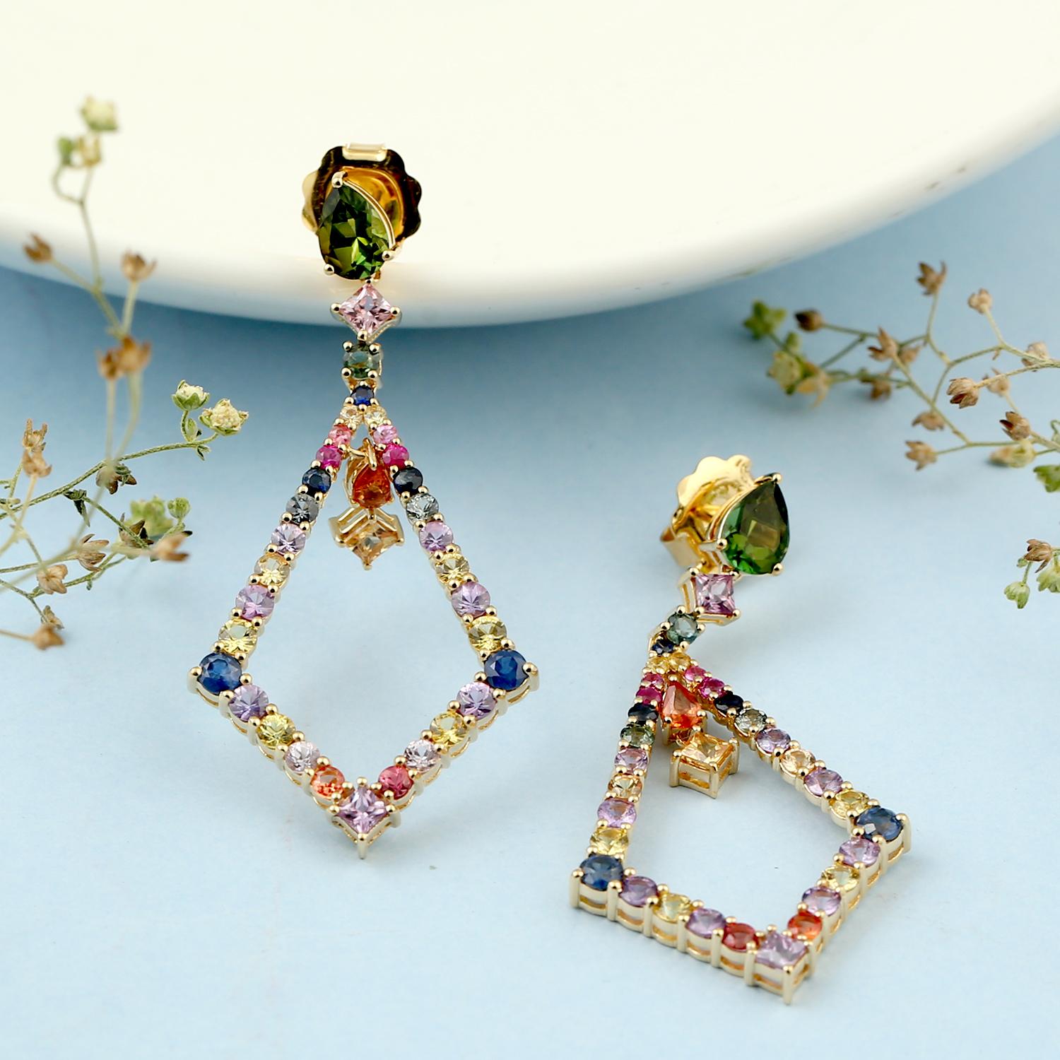 These earrings feature a unique rhombus shape that has been carefully crafted in 18k gold. The rhombus is adorned with a beautiful array of multi-colored sapphires and tourmaline gemstones that add a pop of color and vibrancy to the