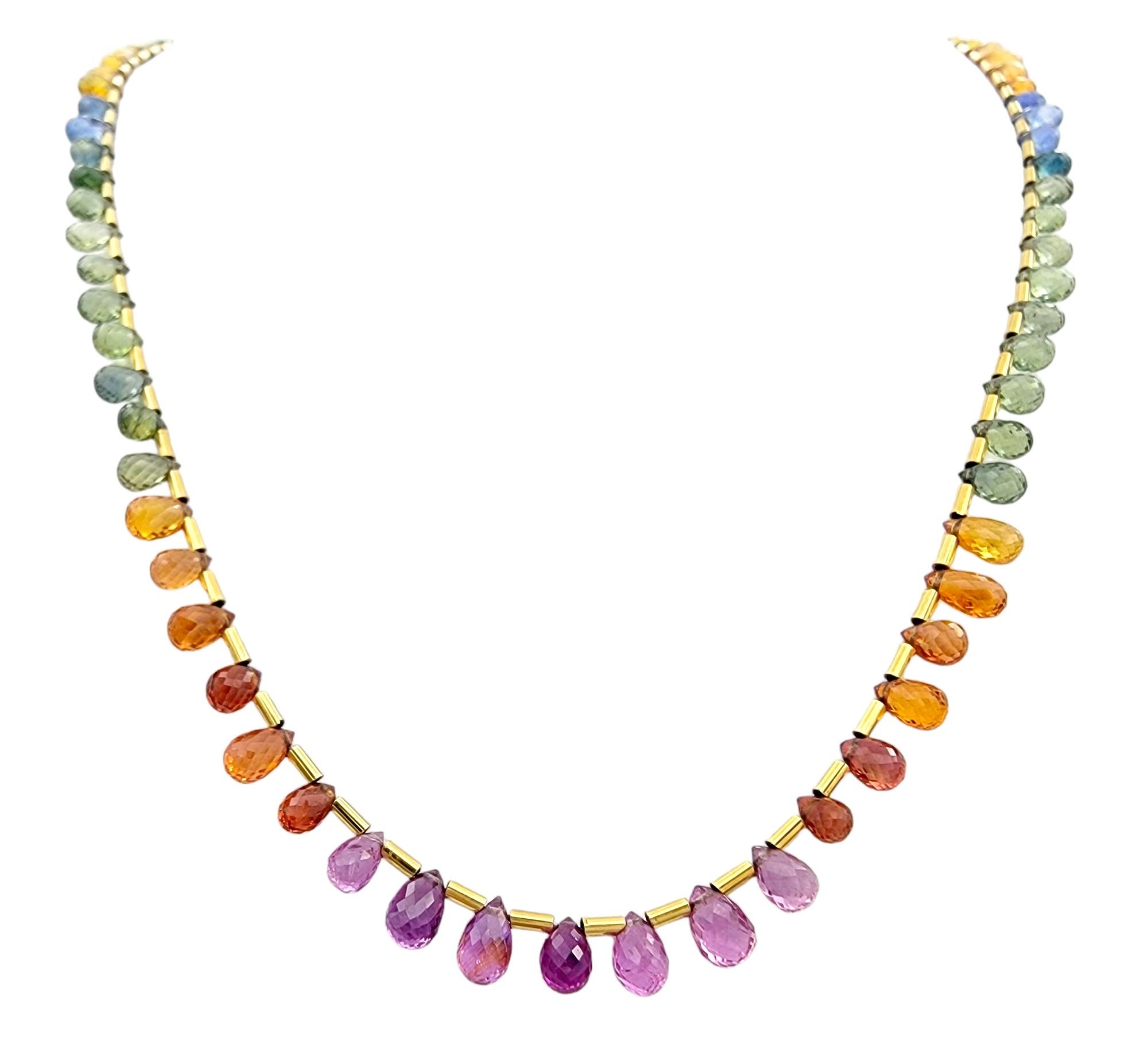 Questa affascinante collana con gemme multicolori penzolanti è realizzata in oro giallo 18 carati lucido. Questo pezzo unico è caratterizzato da una serie di vibranti e colorate gemme briolette che penzolano elegantemente intorno alla collana,
