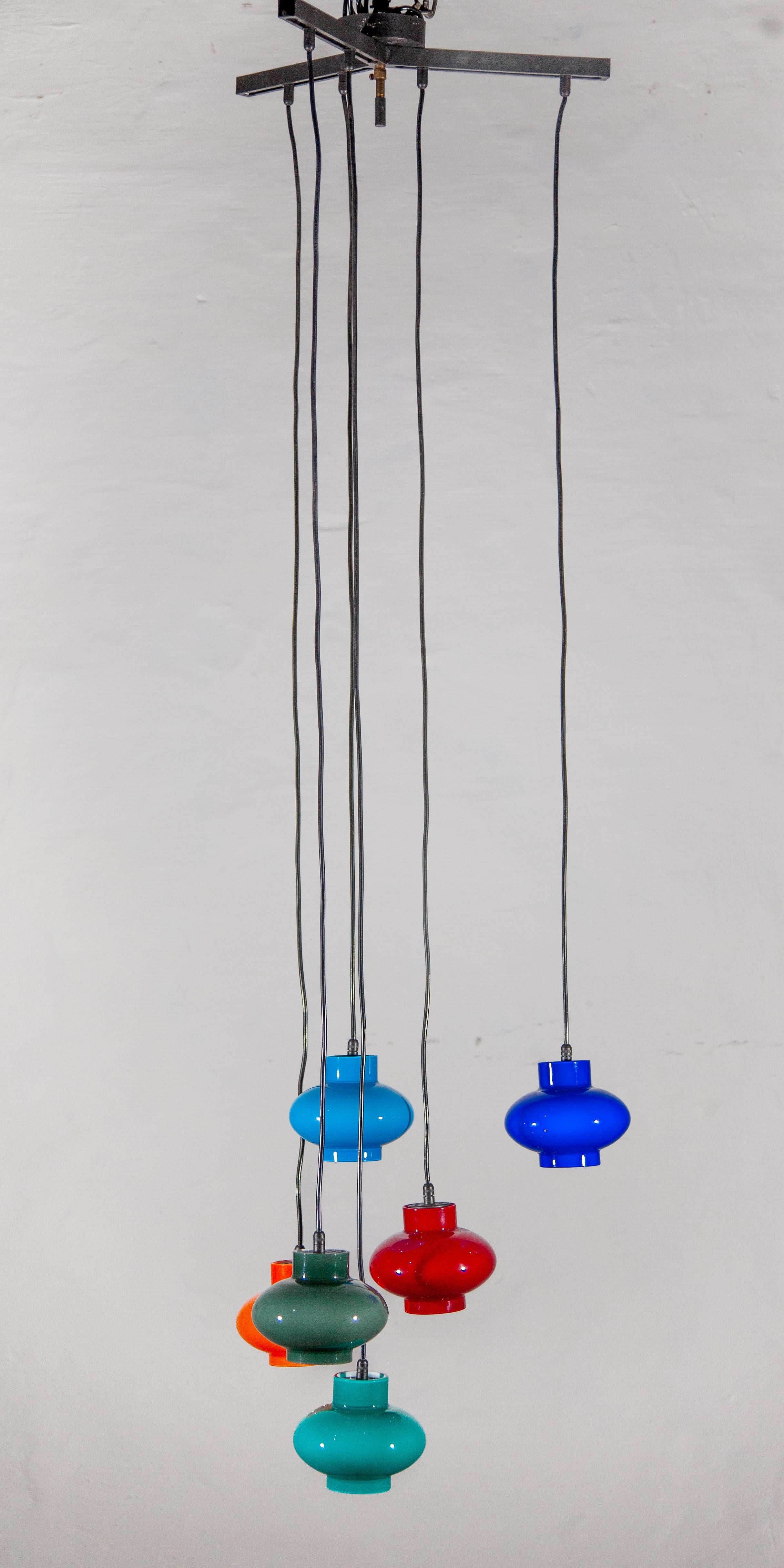 Decorative Mid-Century Modern Six Multi colored, blue, turquoise blue, orange, red green opal glass shades cascading pendant lamp. Designed and manufactured by Peill & Putzler, Germany, 1960s.