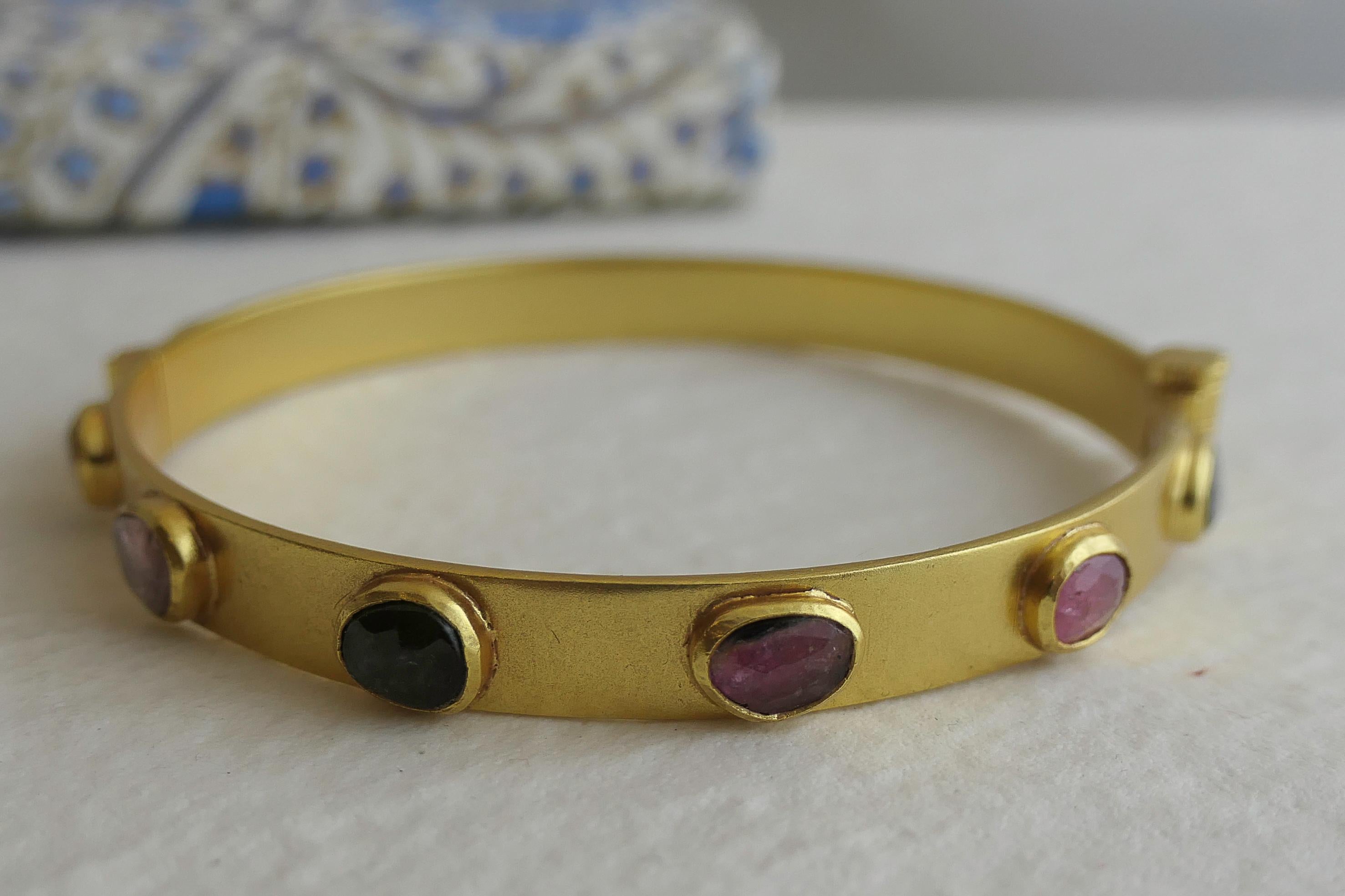 Questo braccialetto bangle ha 12 tormaline multicolore  in argento sterling placcato oro.  Le tormaline sono tagliate a rosa e misurano circa 6-7 mm.  Il bracciale è rotondo e ha un diametro di 6 cm.  Ha un'apertura a vite per indossarlo e