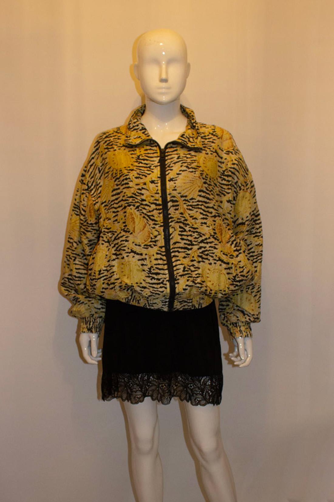 A fun jacket for Fall or late Summer. The jacket is in silk with a shell print design in yellow, caramel , black and ivory.  It has a central zip opening and a pocket on either side. The jacket has elasticated cuffs and hem, and is fully