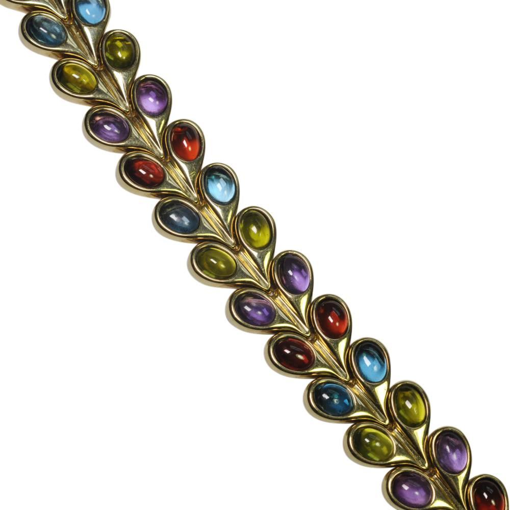 Stylish bracelet set with two rows of oval cabochons in amethyst, peridot, garnet and blue topaz in a rubover setting.  The stones are linked by hinges, making the bracelet supple and comfortable to wear.  It closes with a Tongue clasp and is fitted