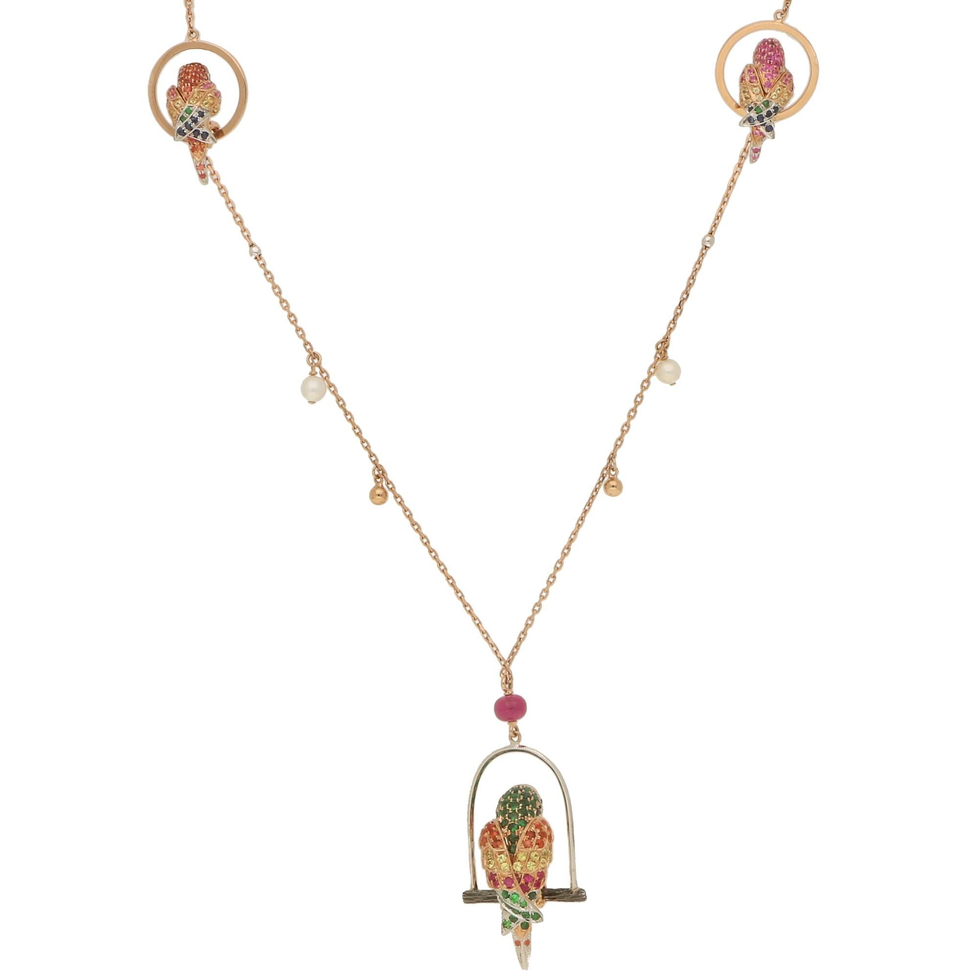 A beautifully unique gem set parrot necklace set in 18k rose and white gold. The necklace is set with three parrots, the biggest of the three being the main feature which is perched on a white gold swing roost. The central bird is grain set with