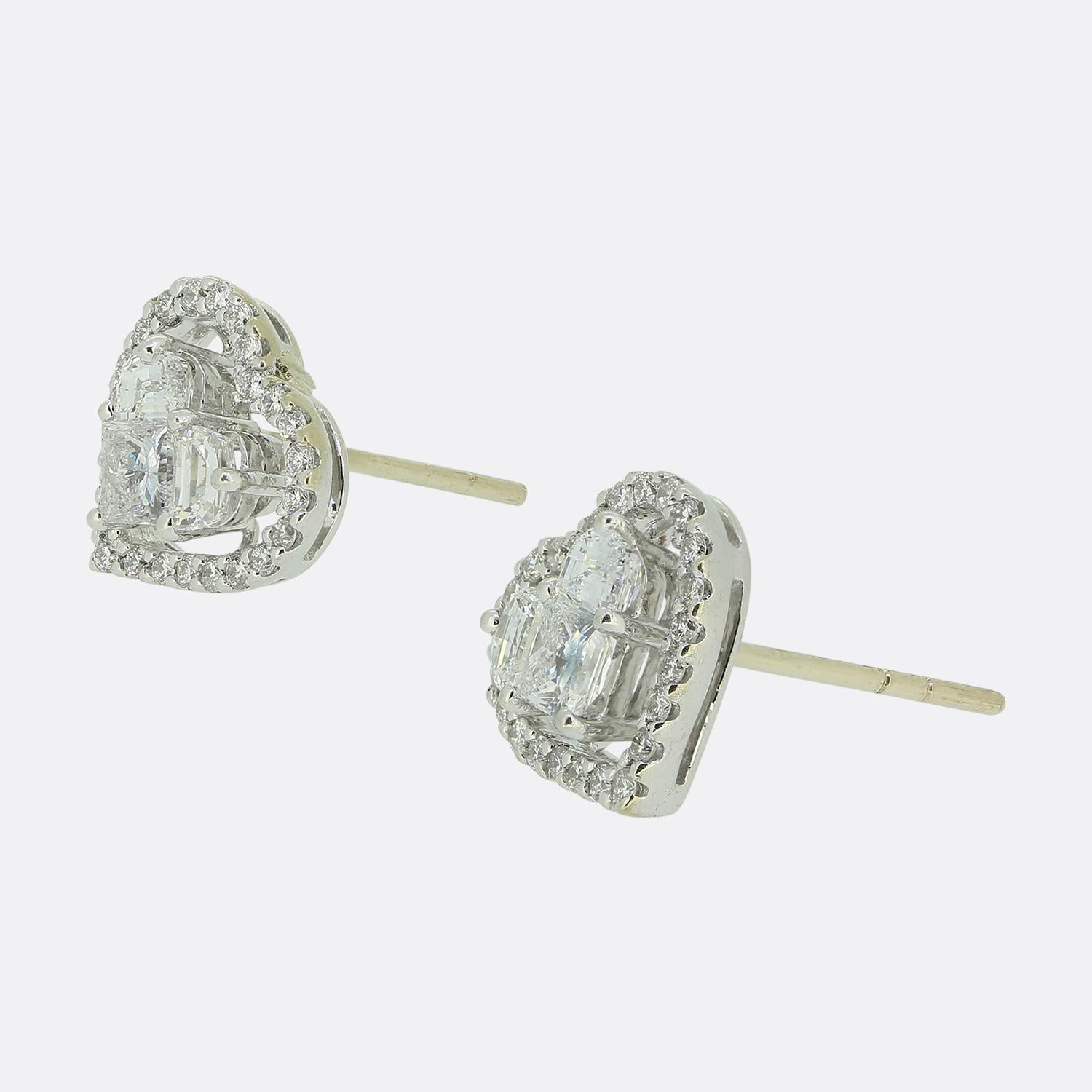 Here we have a beautiful pair of diamond cluster earrings. Each identical 18ct white gold piece features a centralised princess-cut diamond, elegantly topped by two half-moon diamonds before a frame of round brilliant cut diamonds forms the shape of