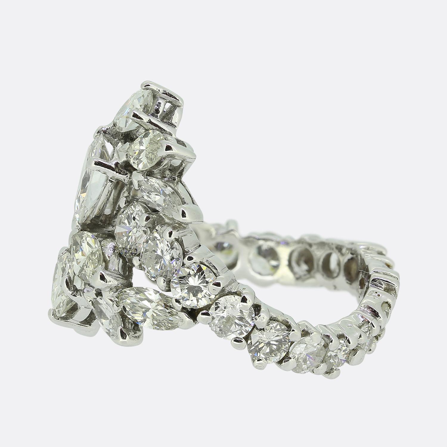 This is a stunning cluster ring featuring a dazzling array of diamonds. At its heart lies a prominent pear-shaped diamond, exuding a bright white hue. Surrounding it are numerous marquise-cut diamonds, each reflecting the same pristine white colour,