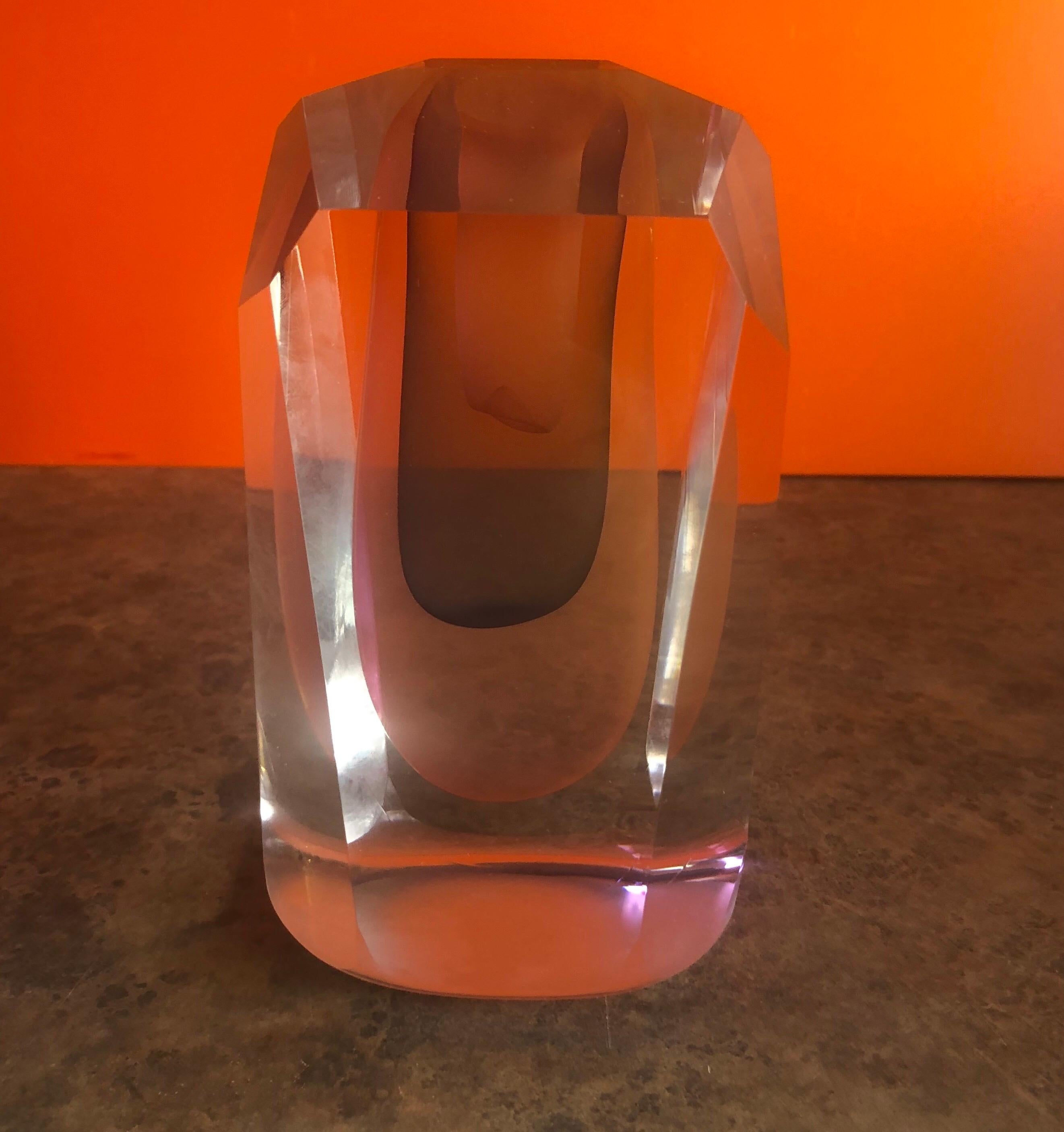 Gorgeous multifaceted (8 planes around the sides forming an uneven octagon and 6 planes on top of the piece) art glass sculpture / oversized paperweight by Ed Nesteruk, circa 1982. The piece is clear glass with two reddish pink and one blue oblong