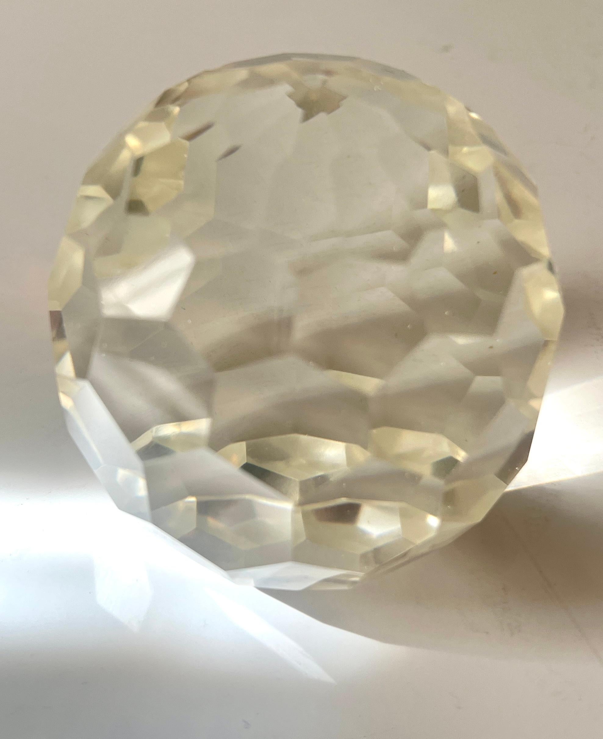 Un peso in cristallo da 3 pollici con molte sfaccettature.  Il pezzo è pesante e può contenere documenti importanti, ma la sua superficie sfaccettata con molti tagli gli permette di essere una parte decorativa di qualsiasi tavolo o scaffale. 

Ne