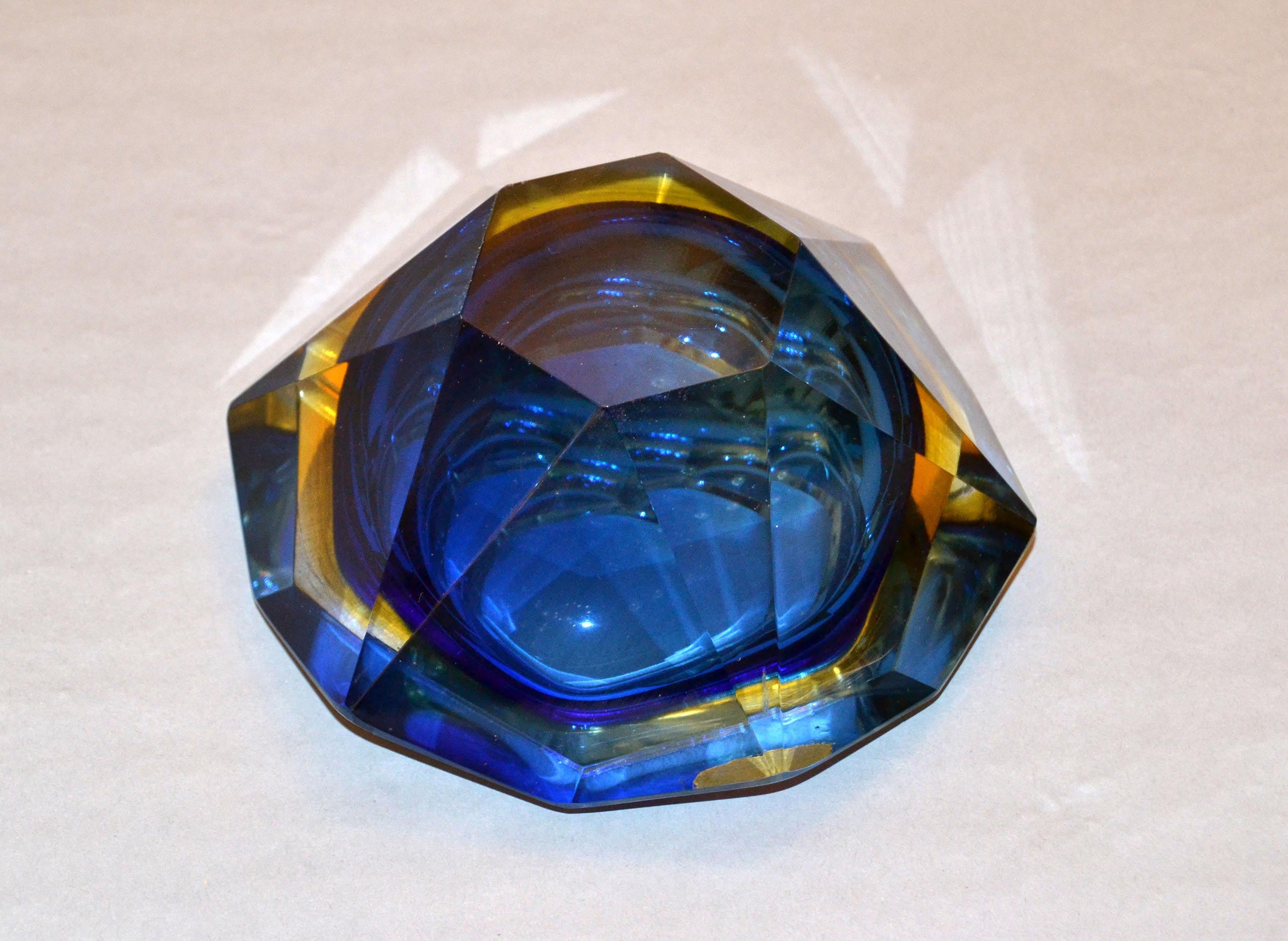 Multifaceted blue, yellow and clear Murano glass ashtray, glass bowl attributed to Flavio Poli by V.A.M. Vetri Molati Murano, Italy.
Blue and amber glass cased into clear glass and a highly decorative twelve faced geometric design.
Original label