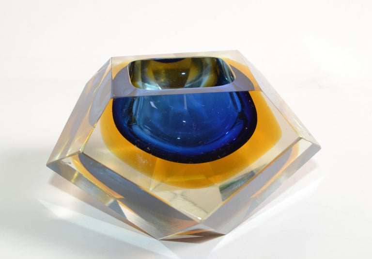 Multifaceted blue, yellow and clear Murano glass ashtray, glass bowl attributed to Flavio Poli by V.A.M. Vetri Molati Murano, Italy.
Blue and amber glass cased into clear glass and a highly decorative twelve faced geometric design.
 