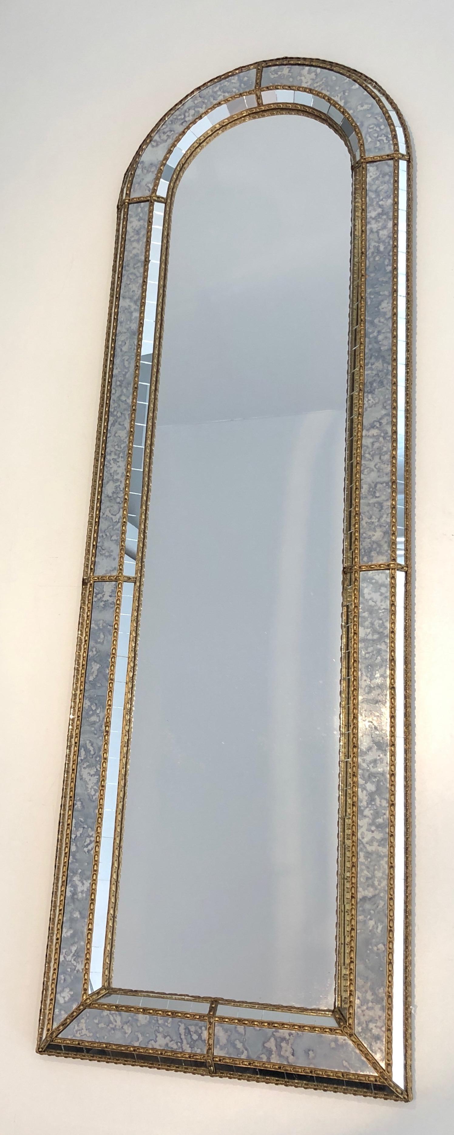 This very nice and decorative mirror is made of multi-facets mirrors with brass garlands. This mirror is rounded on top. This is a French work, circa 1970.