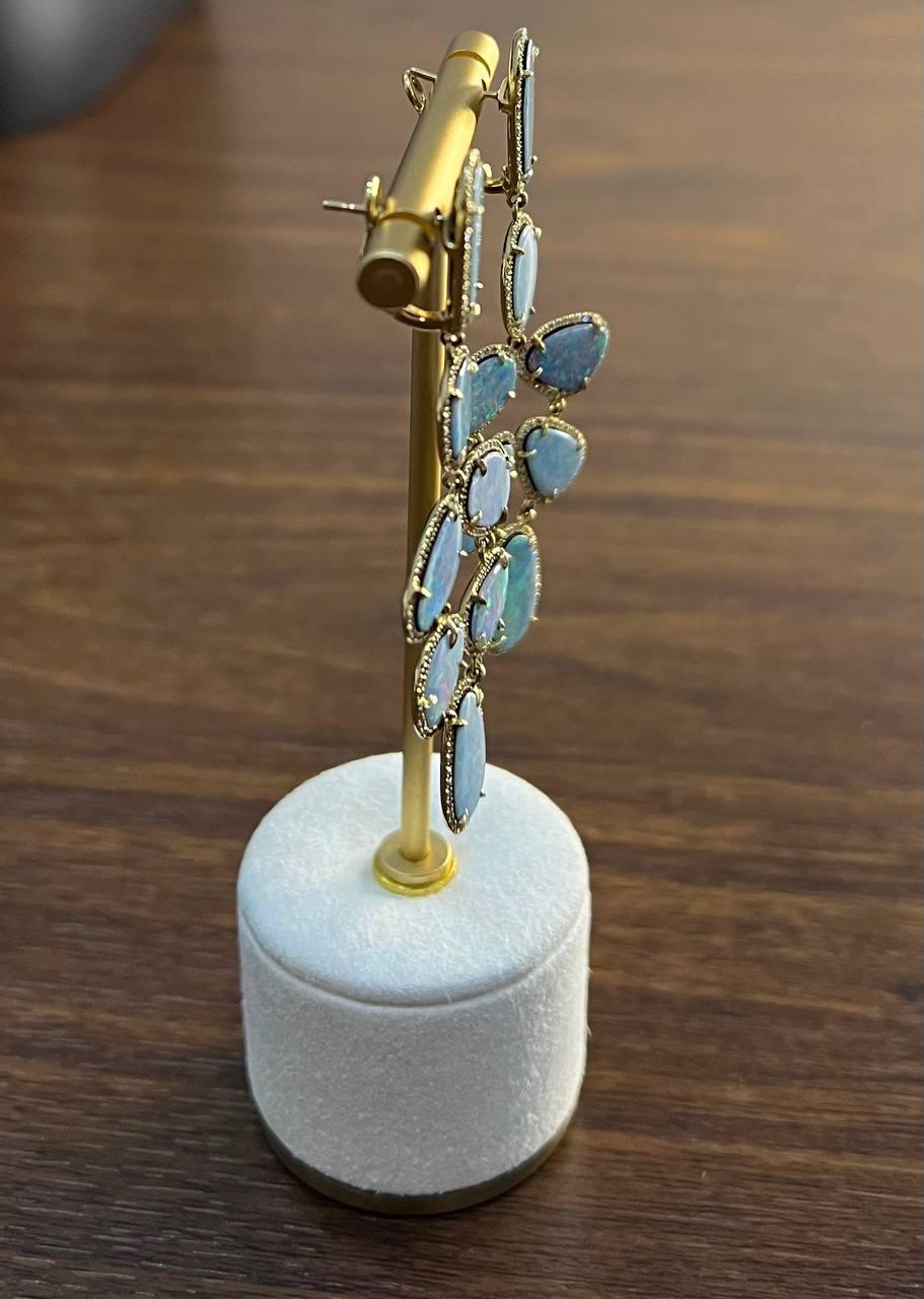 This captivating earring set enchants with its elegant design and shimmering opalescent gemstones. Crafted in 18k gold, it features a cascade of iridescent opal stones (29.57 carats) set in delicate bezels, each stone reflecting a spectrum of