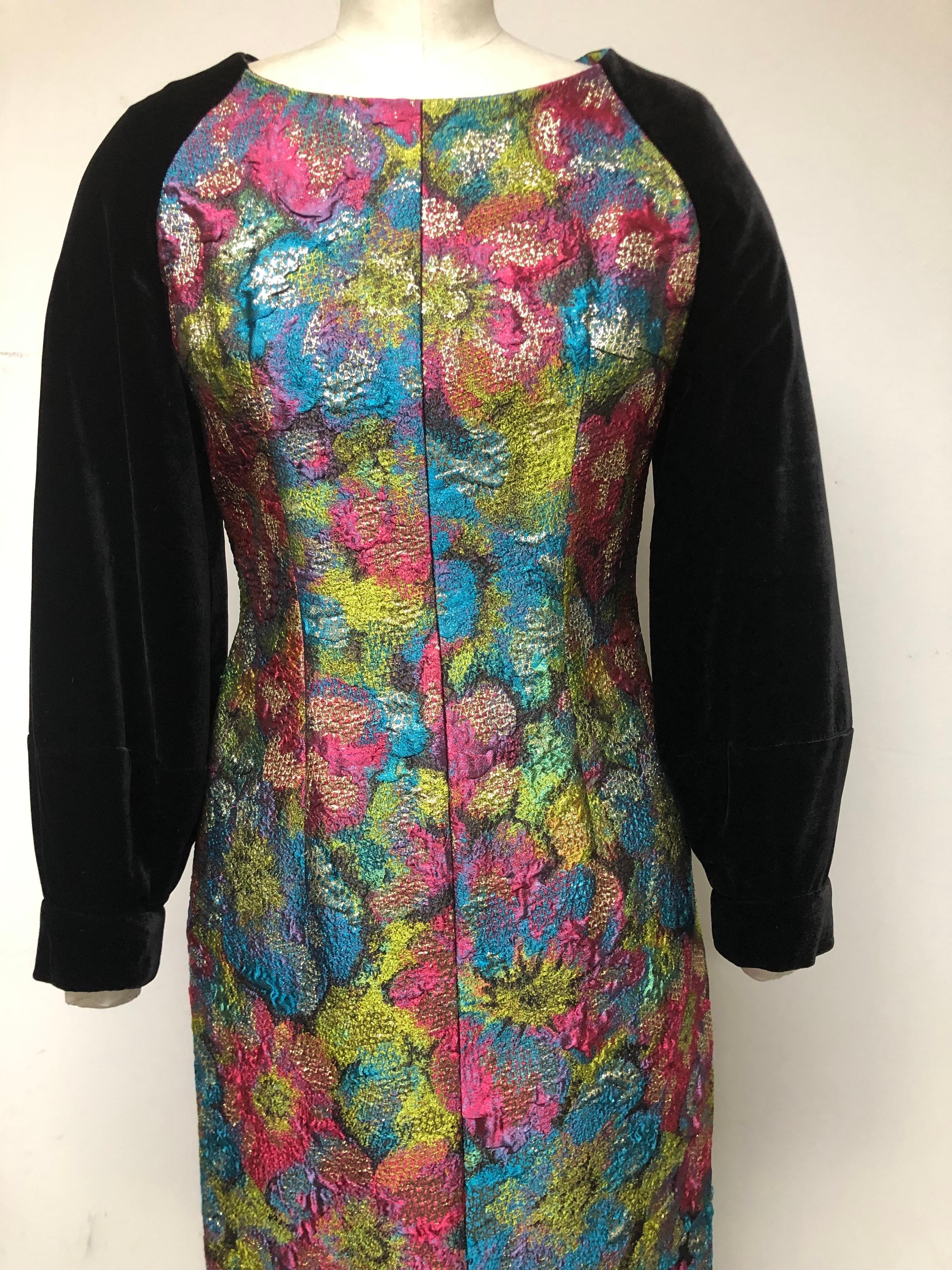 What makes this slim evening dress special is its colorful French brocade with metallic gold highlights. A true couture textile with black silk velvet full sleeve in excellent condition. With a split front. This is a perfect festive holiday dress