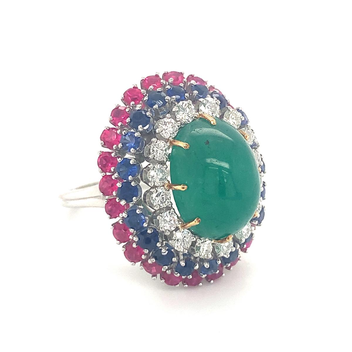 One multi-gemstone bombe form platinum and gold ring featuring one oval cabochon emerald weighing 11 ct., 20 round brilliant cut rubies totaling 2.22 ct. and 24 round brilliant cut sapphires totaling 2.64 ct. Enhanced by 16 round brilliant cut