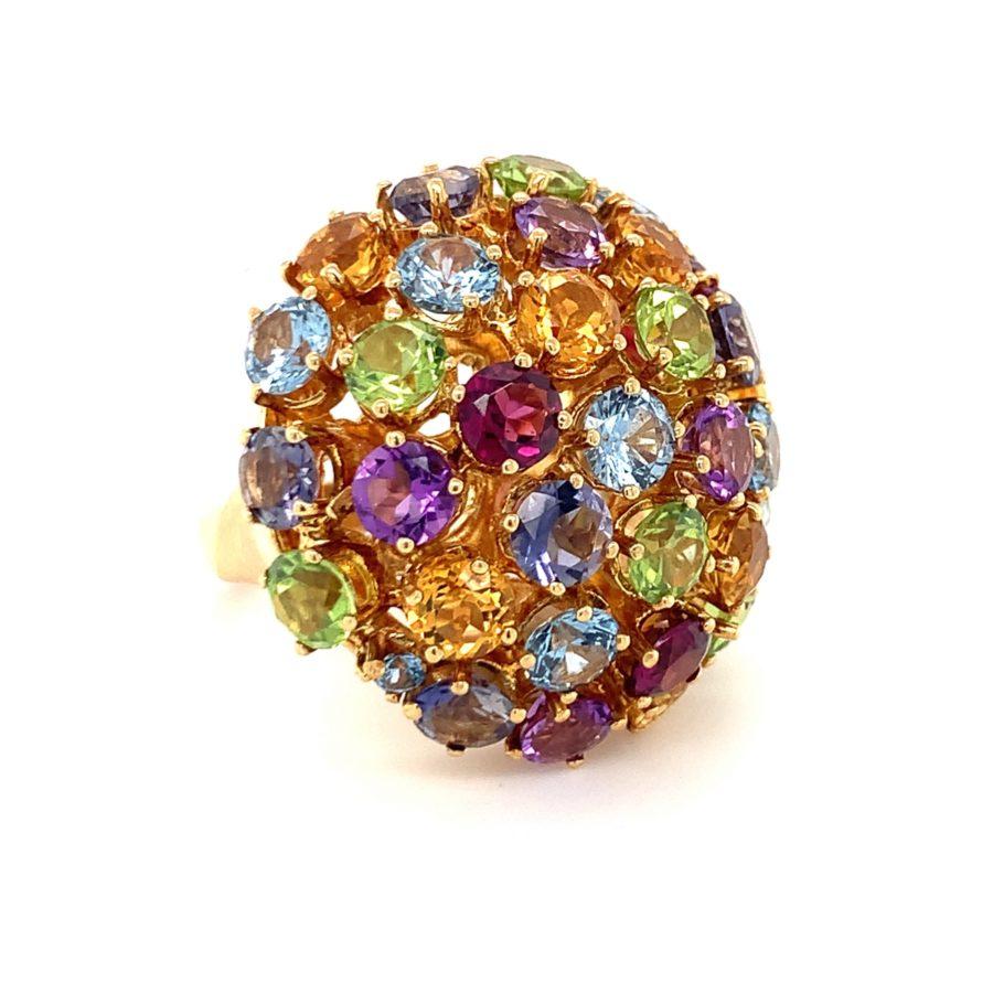 This splendid 1960s Italian-made multi-gem bombe ring is a grand and playful showcase of vibrant colors. Crafted in 18K yellow gold, it features a striking array of 34 round brilliant cut gems, totaling 20 carats, including peridots, amethysts, blue