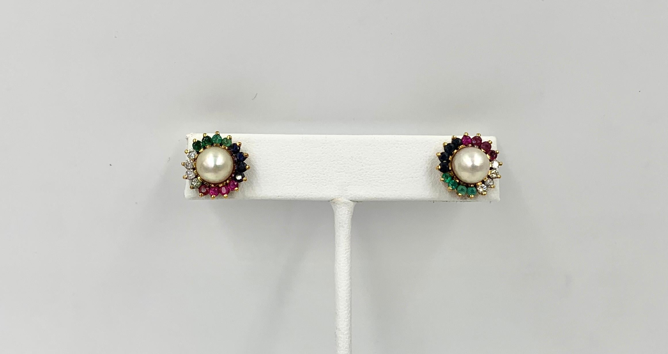 A stunning pair of Multi Gem Earrings with Emerald, Sapphire, Ruby, and Diamond gems surrounding a luscious white Pearl.  Each earring has four Emeralds, Rubies, Sapphires and Diamonds surrounding the 7.5mm pearl.  I love the radiant colors of all