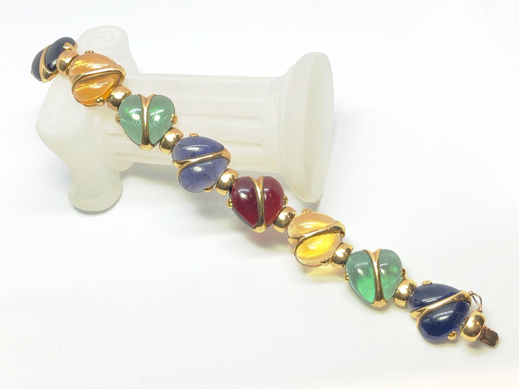 A heart bracelet, with cabochon-cut garnet, citrine, green tourmaline and iolite set, bisected hearts, spaced with covered hinges, mounted in 18ct gold.