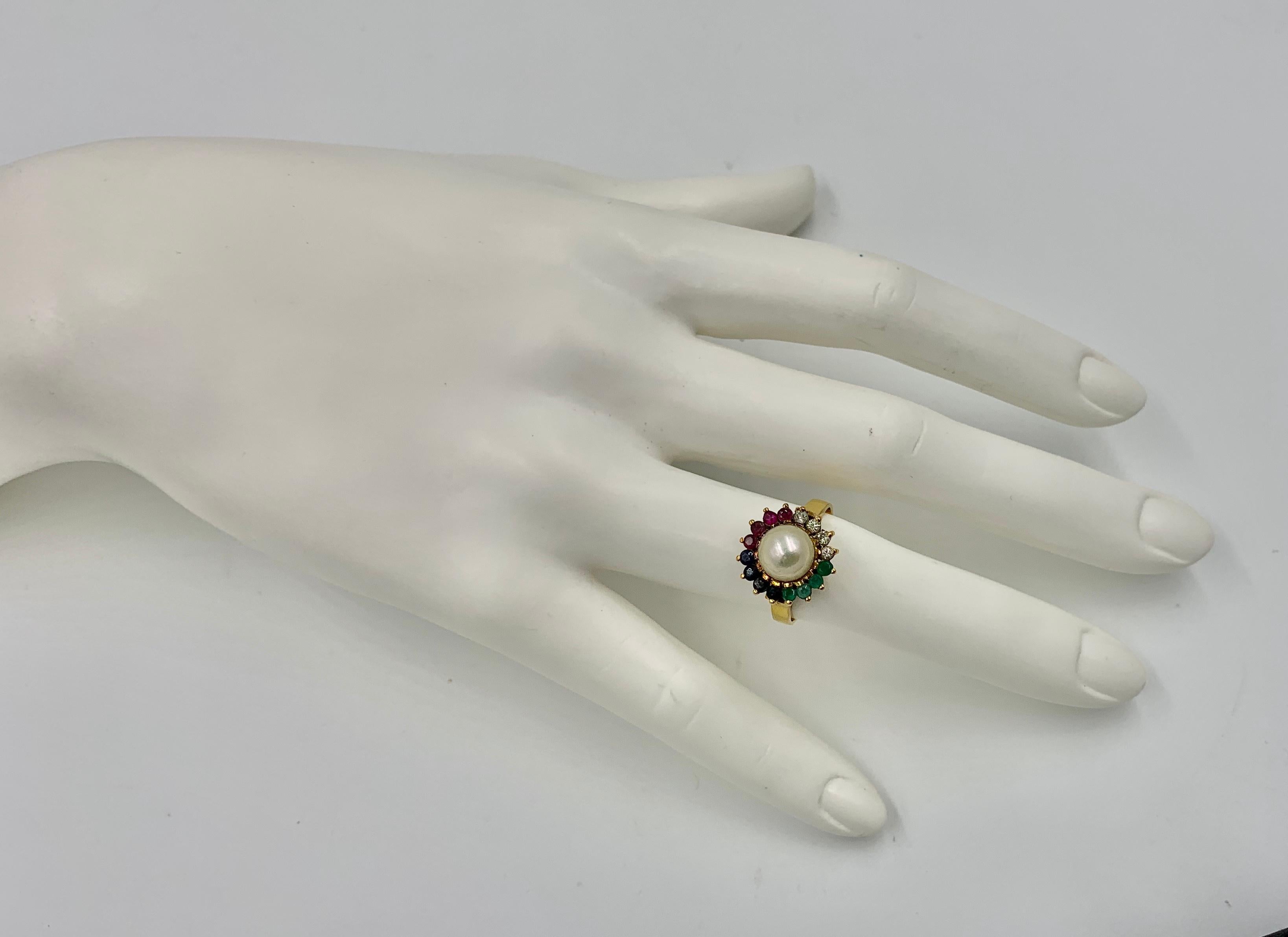 Ein atemberaubender Multi-Edelstein-Ring mit Smaragd, Saphir, Rubin und Diamanten, die eine üppige weiße Perle umgeben.  Der Ring besteht aus vier Smaragden, Rubinen, Saphiren und Diamanten, die die 8 mm große Perle umgeben.  Ich liebe die