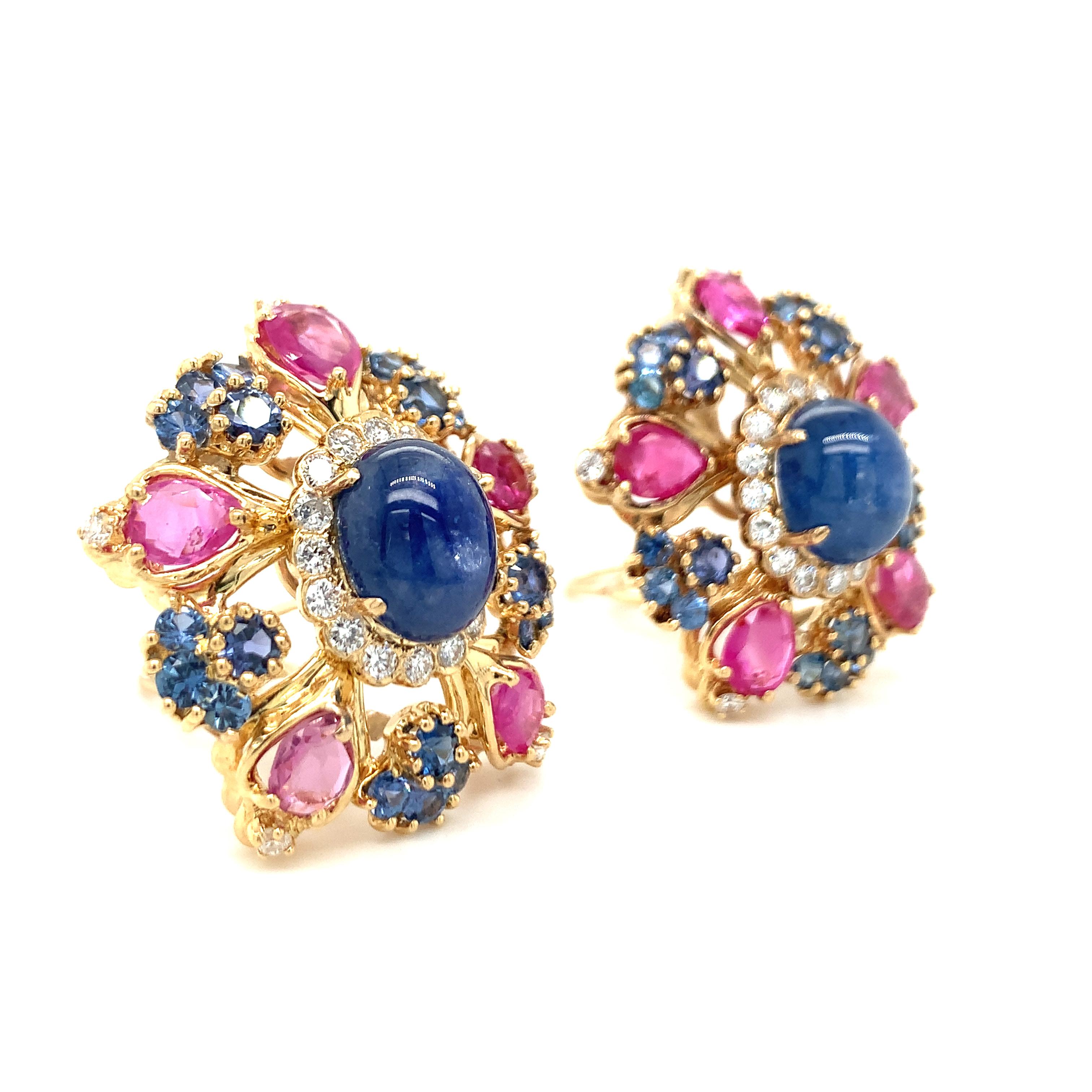 One pair of multi-gem set 18K yellow gold earrings centering two oval cabochon, blue sapphires totaling 12.50 ct. accented by 40 round brilliant cut blue sapphires weighing 5 ct. in total. The earrings are further accented by 10 marquise cut pink