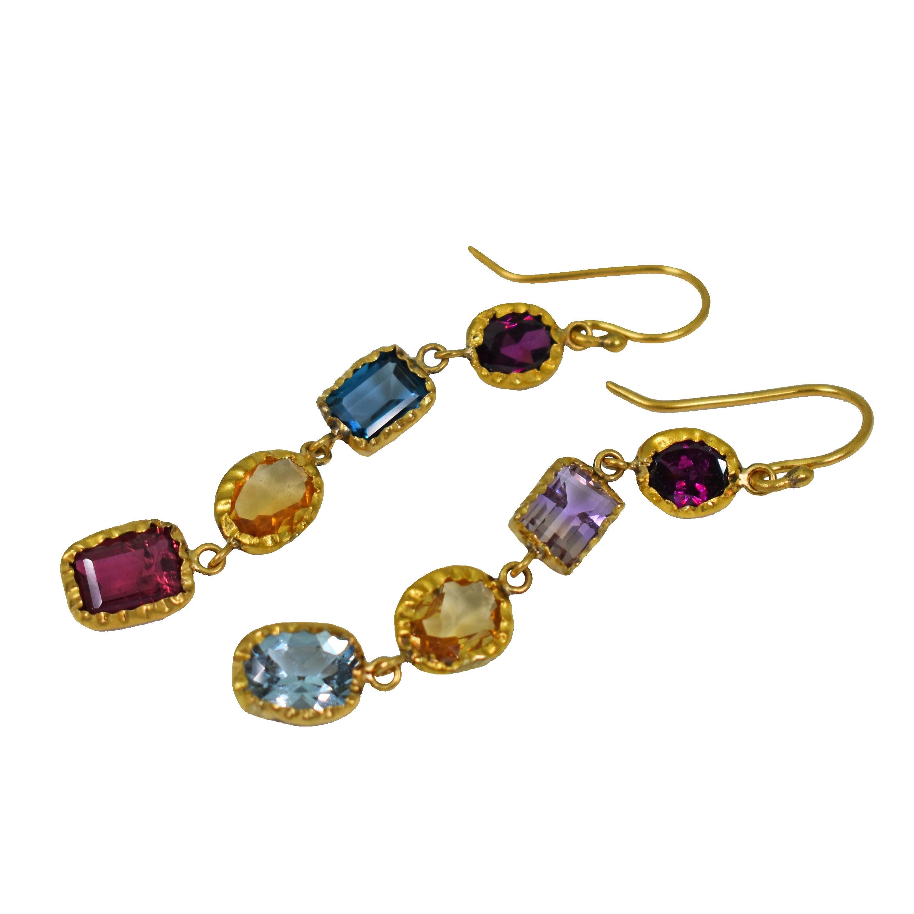 Colorful, multi-gemstone asymmetrical dangle earrings wrapped in 22k yellow gold. Gemstones include Rhodolite Garnet, Ametrine, Blue Topaz, Citrine, Aquamarine and Pink Tourmaline. Dangle earrings are 2.5 inches in length and come with silicone