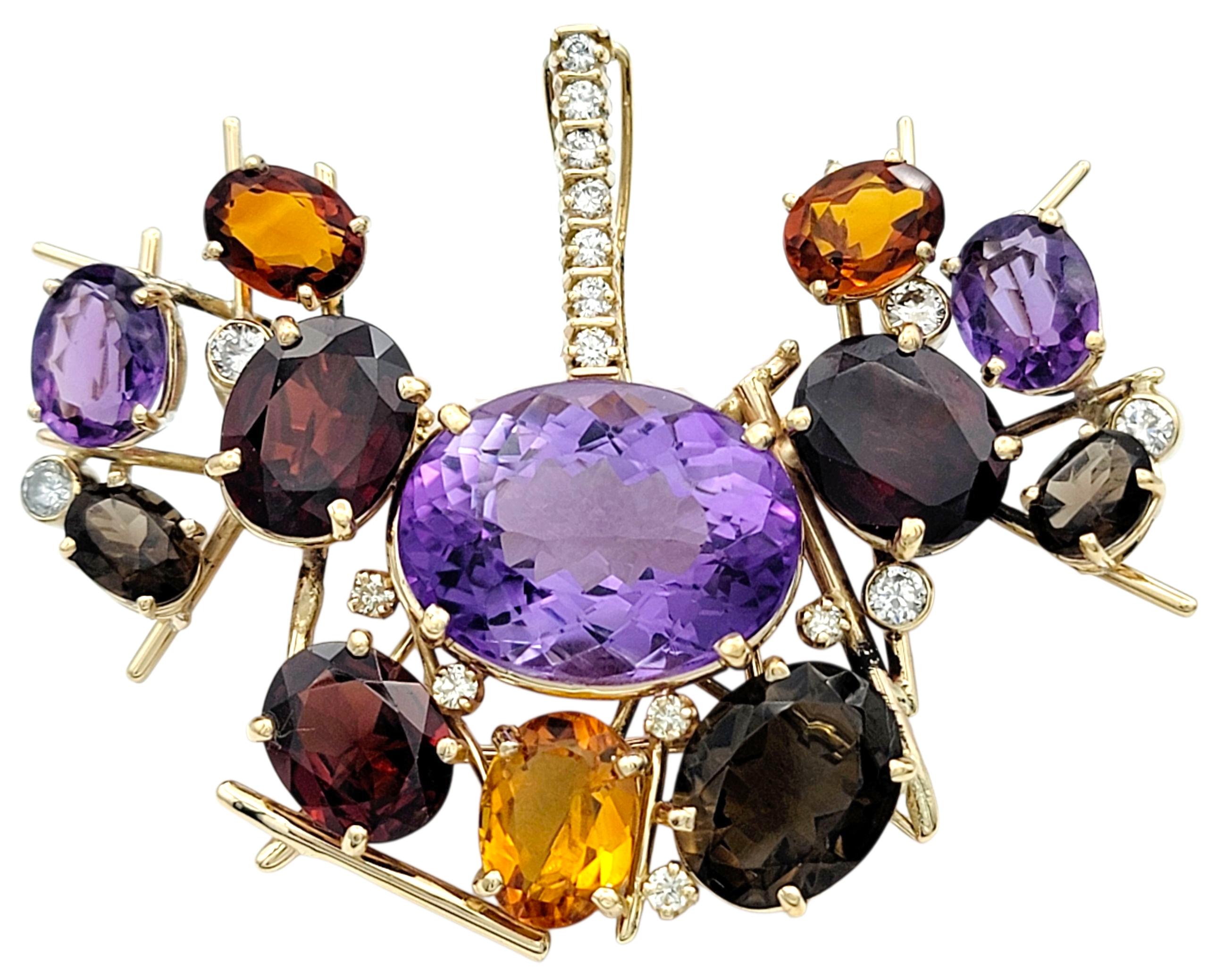 Cette broche audacieuse est une vitrine d'art et de couleur, réalisée en or jaune 14 carats. Au centre, une grande améthyste ovale est entourée de citrines, de grenats, de quartz fumé et d'autres améthystes, le tout rehaussé de diamants étincelants.