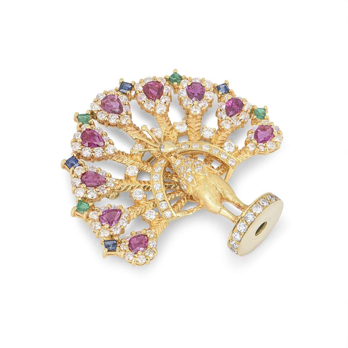 A wonderful 18k yellow gold multi gem set Peacock brooch. The brooch comprises of a peacock open work design and is pave set with round brilliant cut diamond feathers totalling 2.20ct, each feather is complemented by a pear shaped ruby set to the