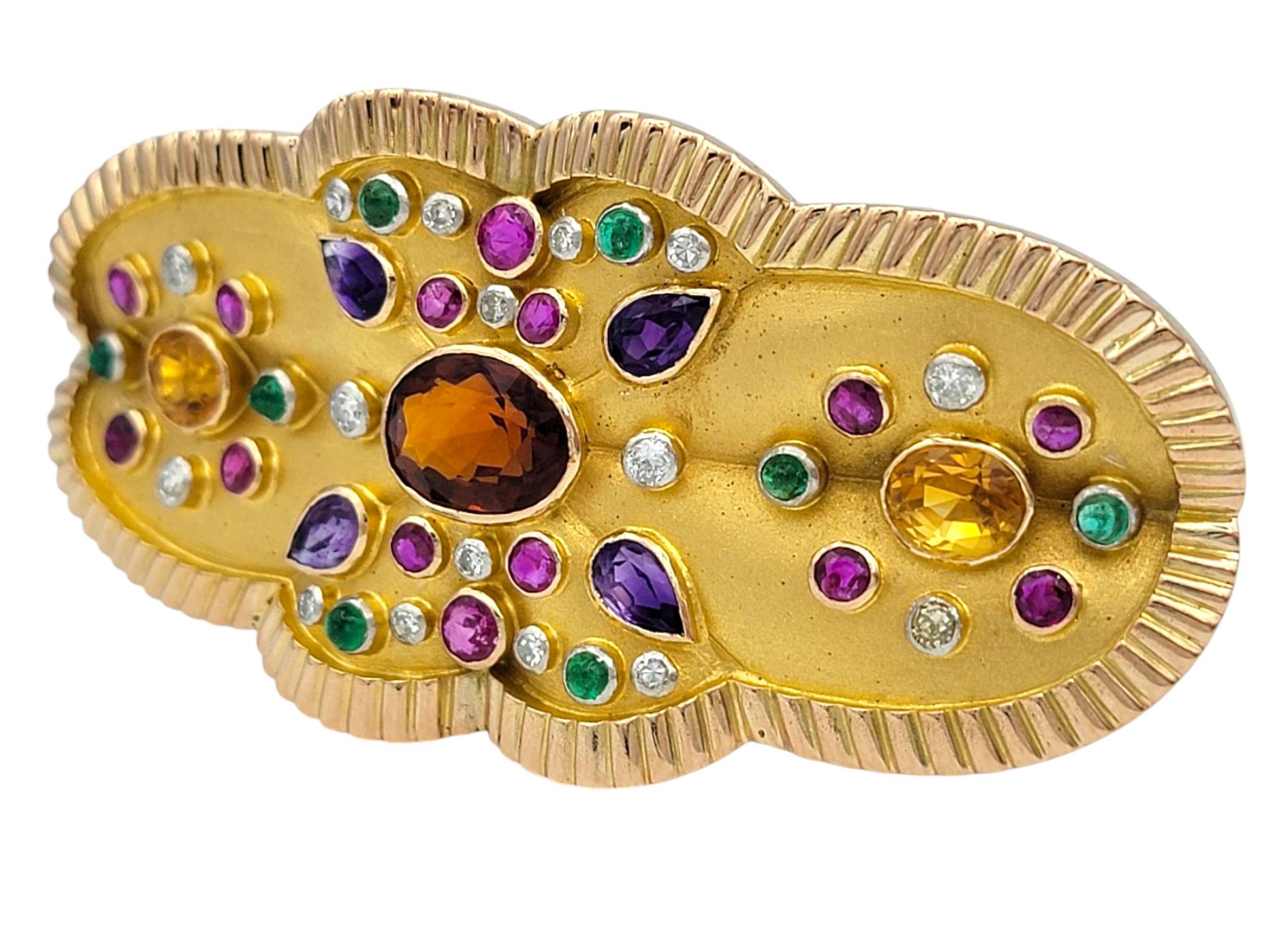 This exquisite brooch, crafted in 14 karat yellow gold, showcases a refined sandblast finish with a polished ridged trim, enhancing its vintage-inspired elegance. At its center, a luminous citrine is surrounded by a dazzling array of diamonds,