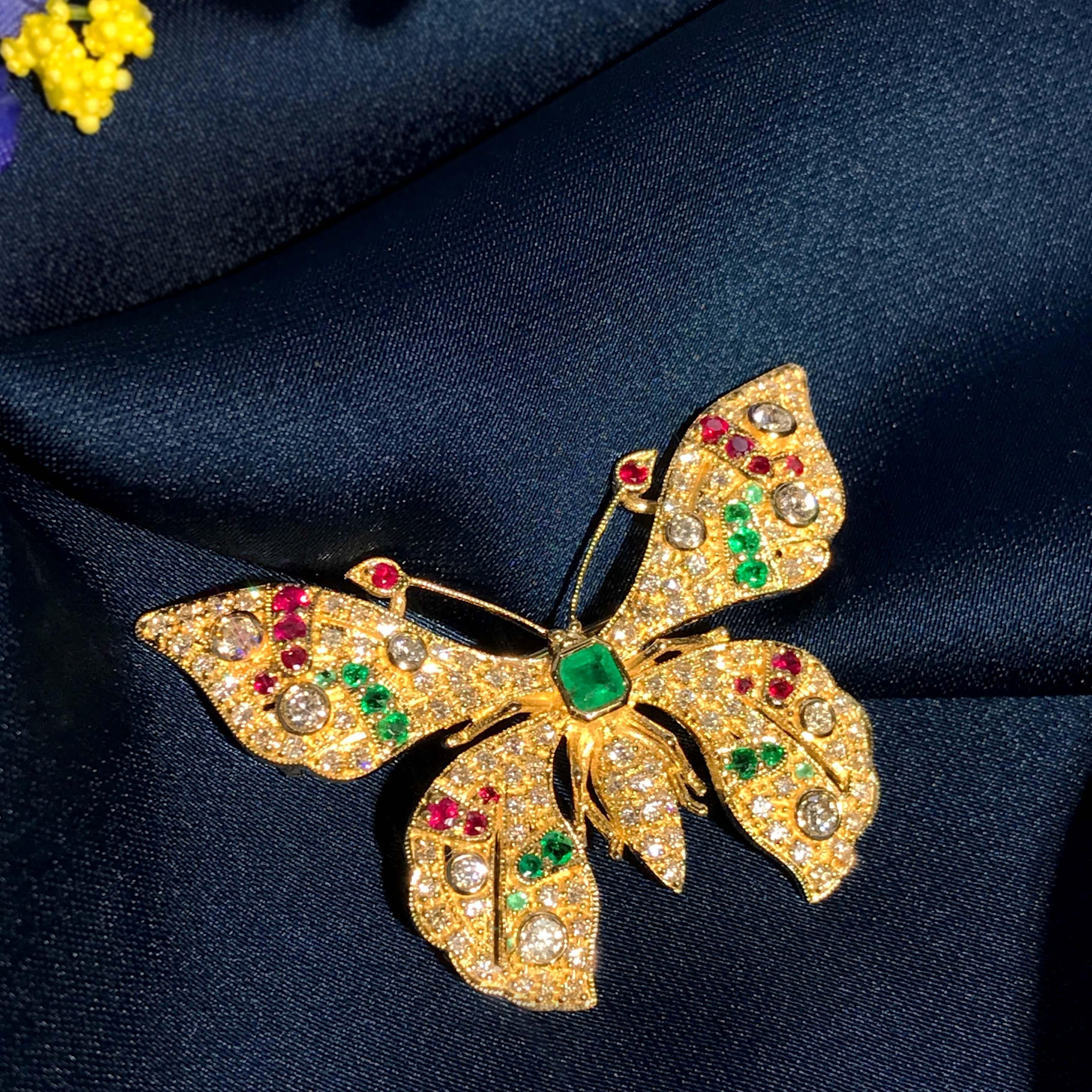 La spilla a forma di farfalla è finemente realizzata in oro giallo 14k. La spilla è impreziosita da uno smeraldo verde vibrante taglio asscher per il corpo. Decorata con diamanti, rubini e smeraldi sulle ali, questa spilla è simbolo di bellezza,