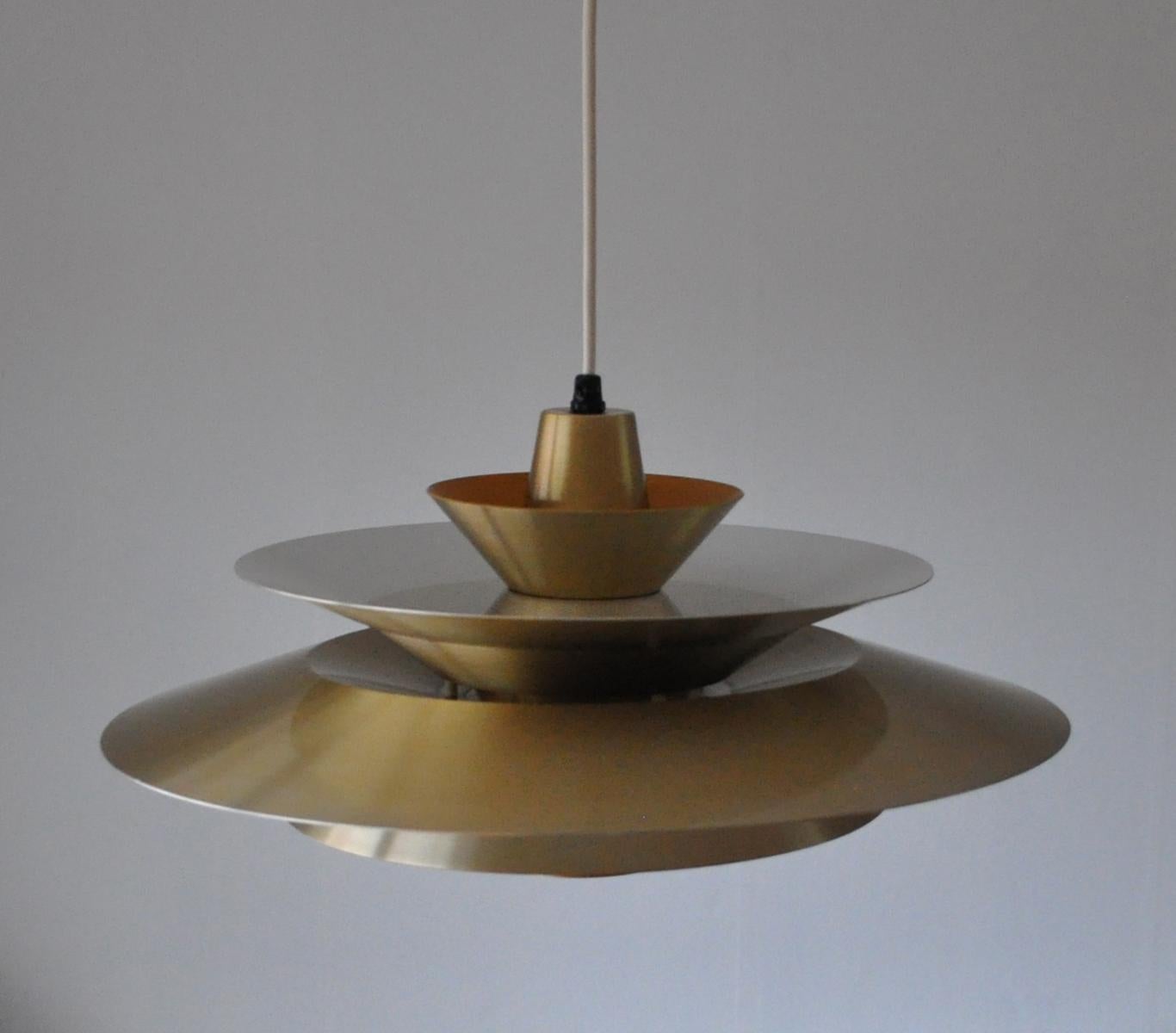 Multi-layered brass pendant lamp with orange and white inner shades which gives pleasant warm light when lit.
Designed by Lyskær Belysning in Denmark in the 1960s.

Very good vintage condition with small signs of wear consistent with age and