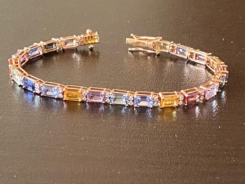 Emerald cut sapphires set in 18K rose gold. The emerald stones are mixed color sapphires. The emeralds are set horizontal with 2 round diamonds in between each emerald. The total carat weight of the bracelet is 14.75 carats. The diamond weight is