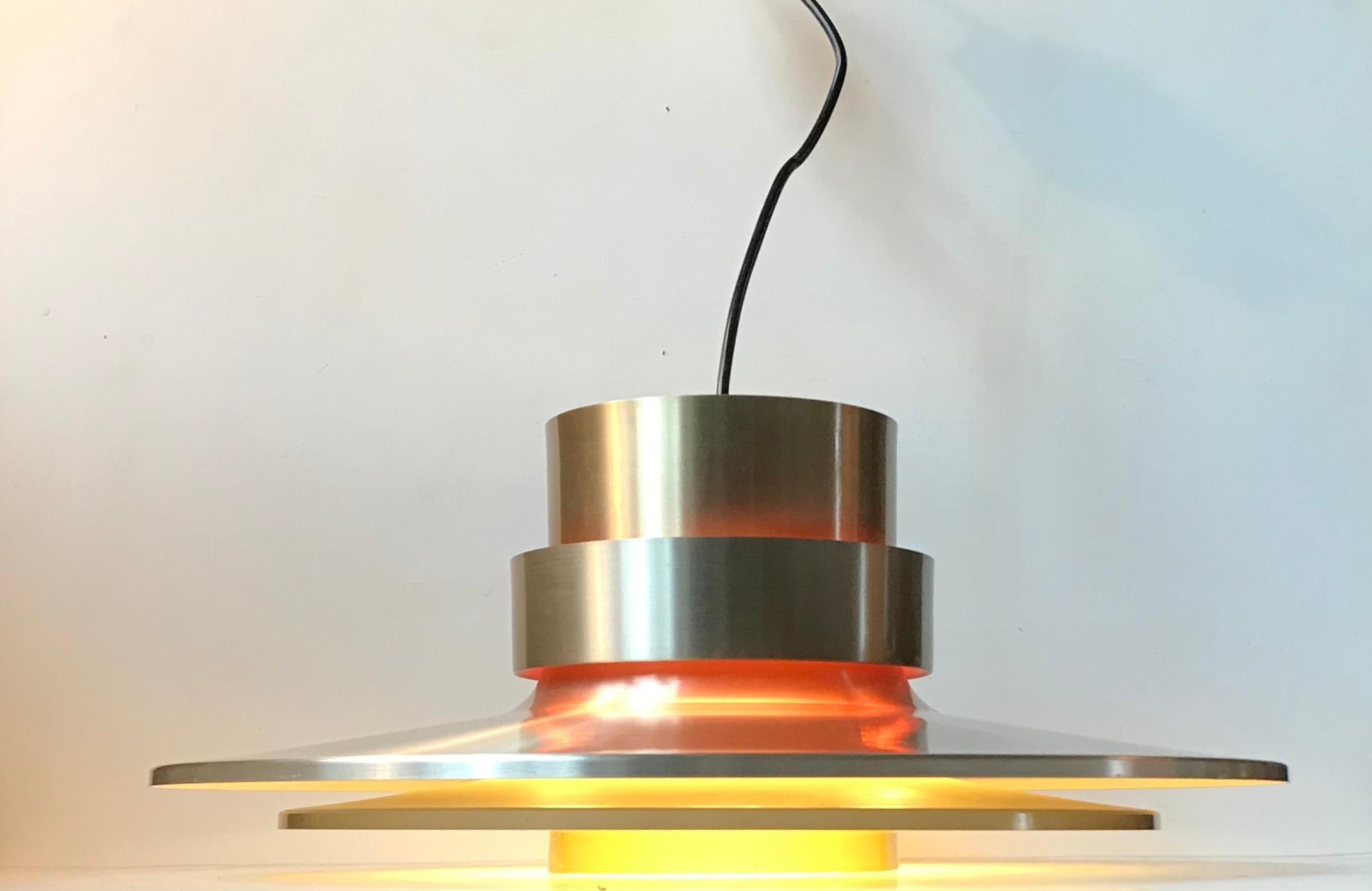 Tiered pendant lamp designed by Sigurd Lindkvist alias Carl Thore and manufactured by Granhaga Metallindustri in Sweden during the 1960s or early 1970s. It is made from aluminium alloy'ed with brass. The inside is white with orange light softening