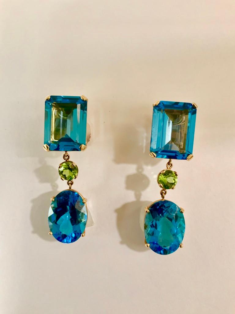 18kt Yellow Gold Multi Shaped Blue Topaz and Peridot Long Earring with Rectangular blue topaz, round Peridot and Oval Blue Topaz Drop.

The elegant earrings measure 2 1/4