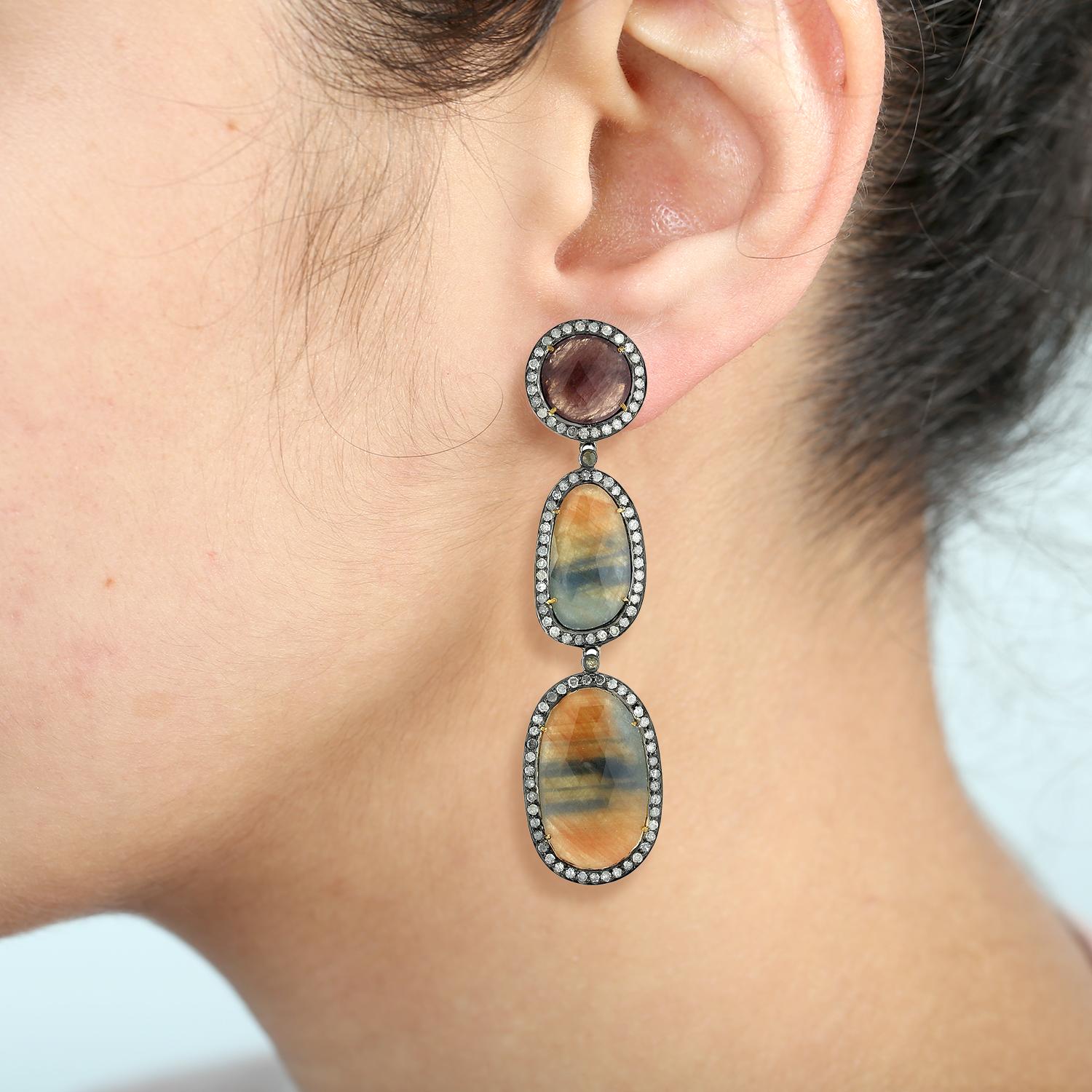 Enhance your jewelry collection with these captivating Multi Sapphire Earrings. Expertly crafted in 18k gold, these earrings feature a striking combination of different shaped and multi-colored sapphires, creating a unique and eye-catching design.