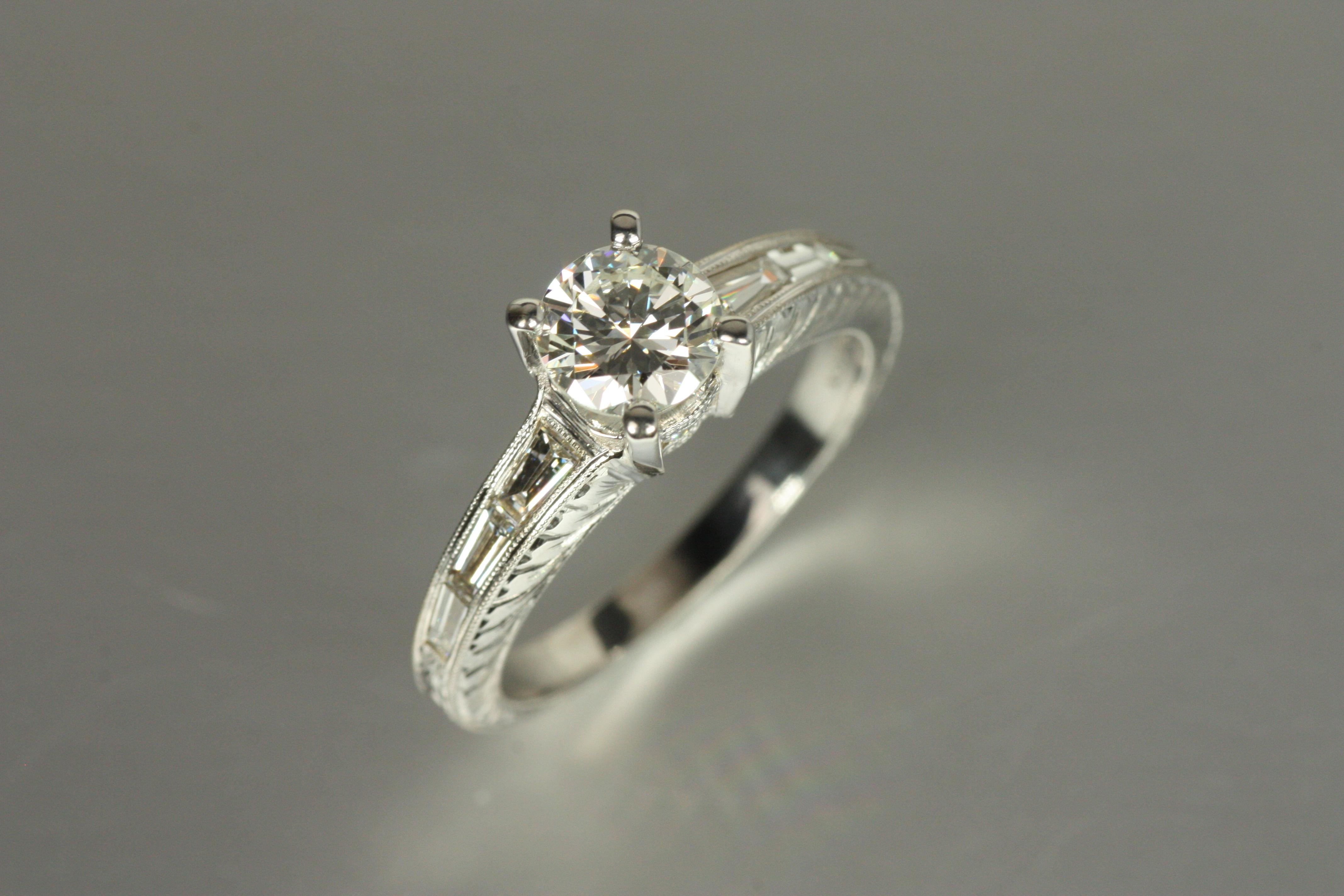 Dieser Verlobungsring aus 18 Karat Weißgold wurde im Hinblick auf dauerhafte Schönheit entworfen und präsentiert in seiner Mitte einen runden Diamanten im Brillantschliff von 0,73 Karat, der klassische Eleganz ausstrahlt. Flankiert von Baguette- und
